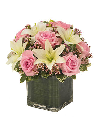Pink roses and white lilies arranged in a square glass vase
