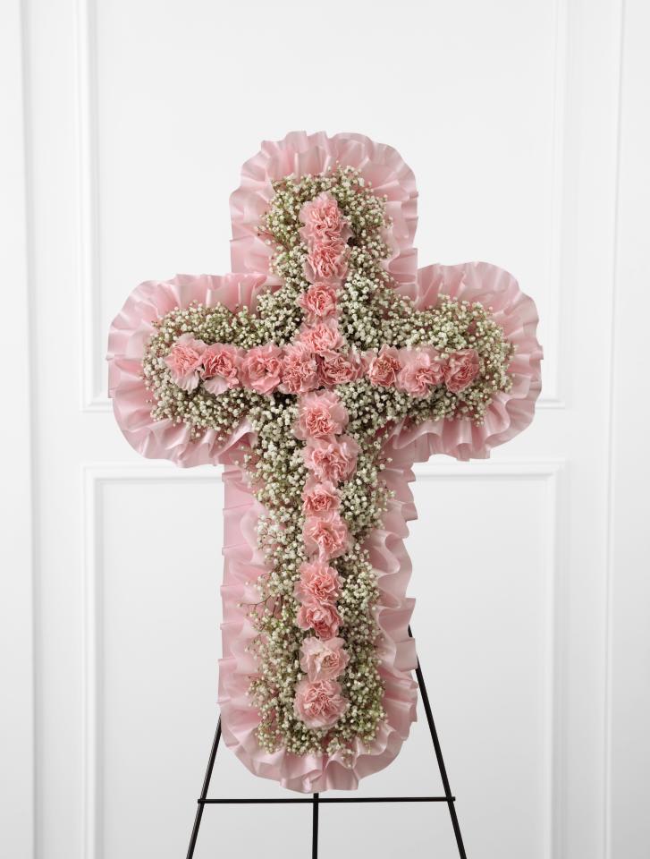 Angel's Cross Easel - TheAngel's Cross Easel is a graceful tribute to honor the  life and faith of the deceased. Pink mini carnations and baby's breath  are lovingly arranged in the shape of a cross, accented with a pink  satin ribbon around the outside and displayed on a wire easel, to create  a wonderful way to express your love for the departed.   24""h x 15""w