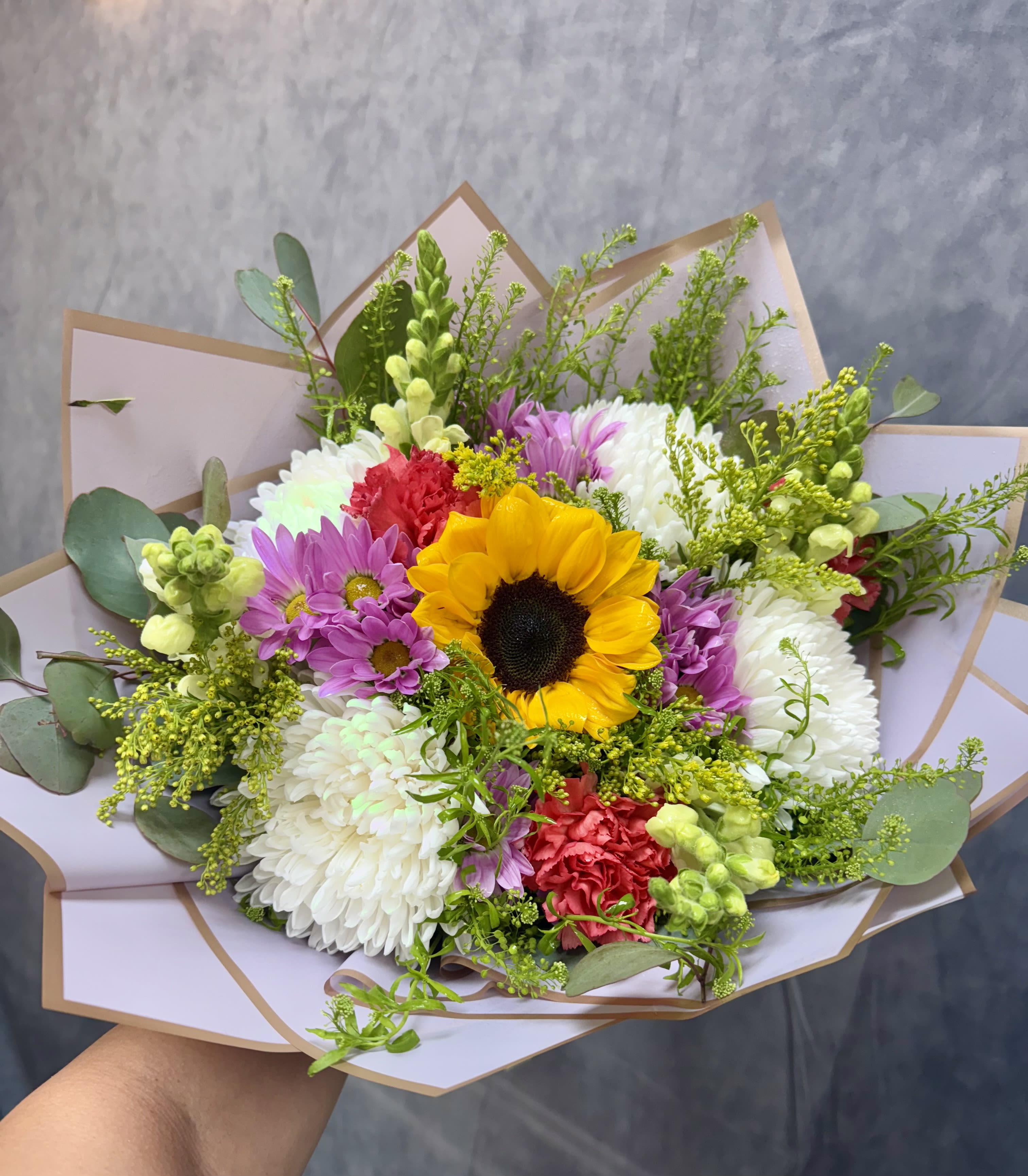 Bouquet with a sunflower, chrysanthemums, and carnations in pastel wrap