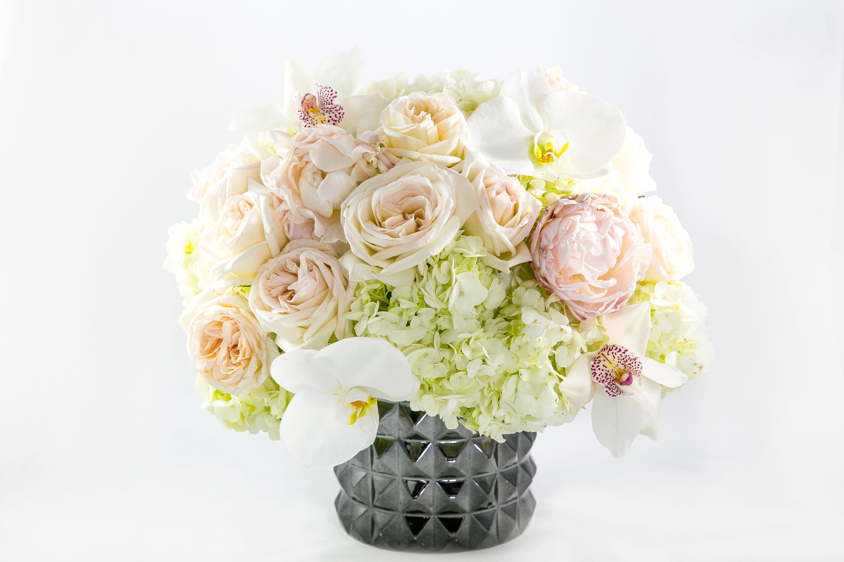 Cream and white floral arrangement in a dark textured vase