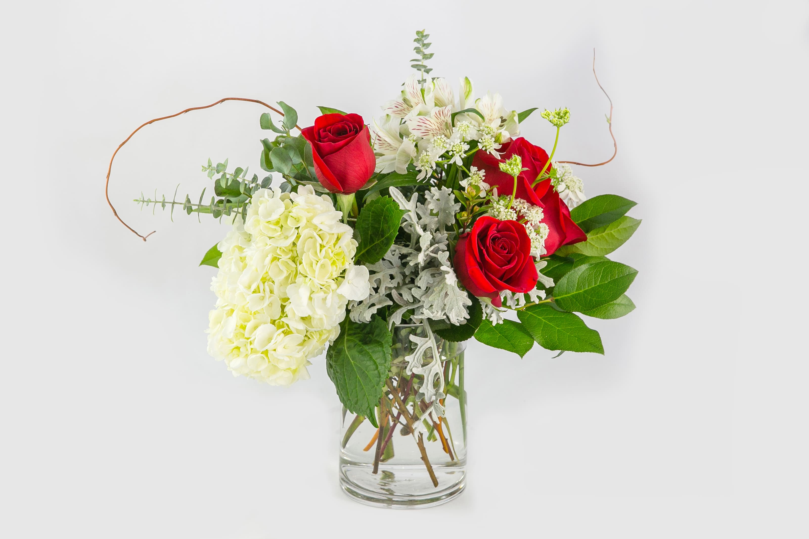 Red roses and white hydrangea in a clear glass vase