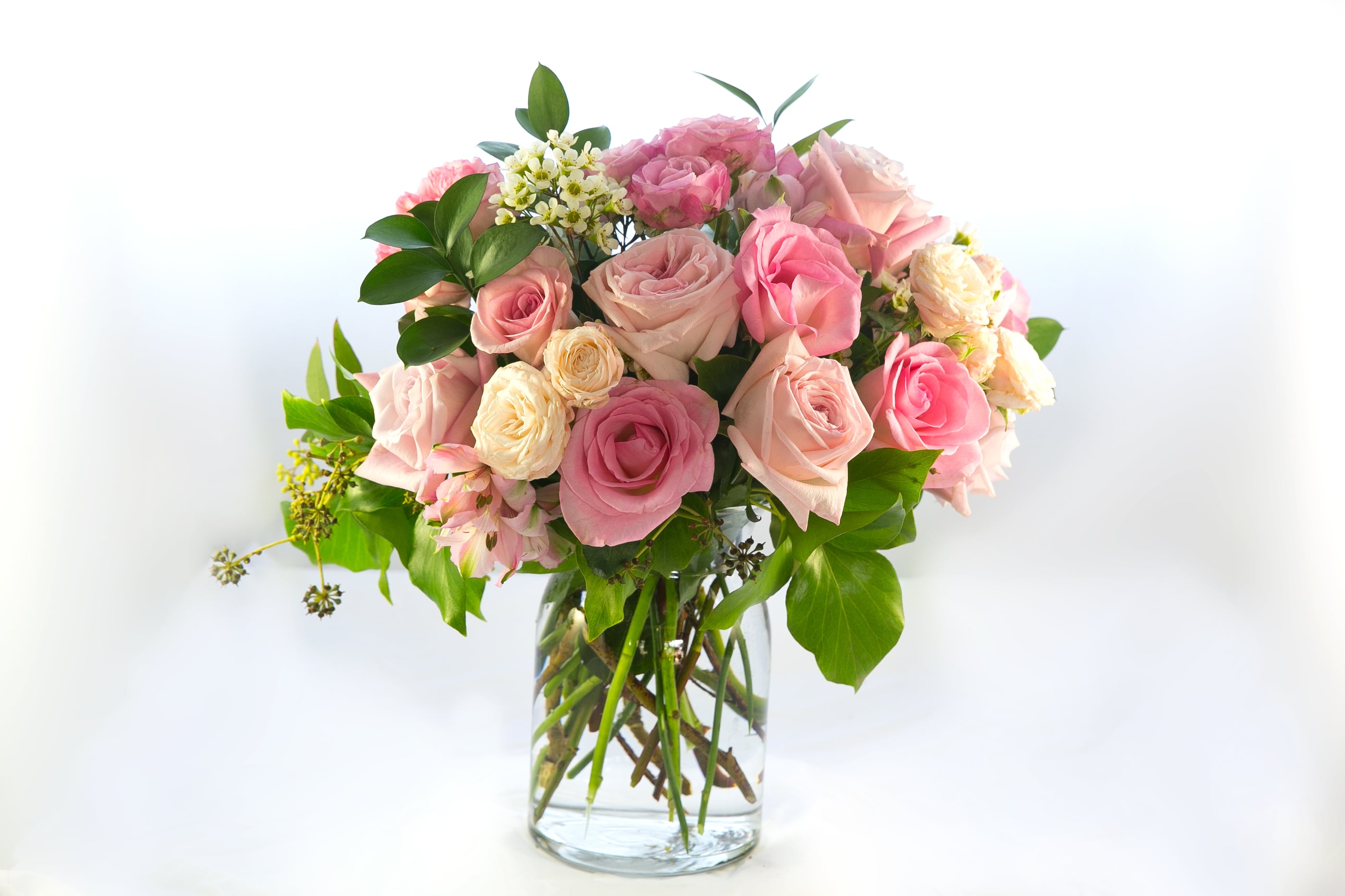 Pink and cream roses arranged in a clear glass vase