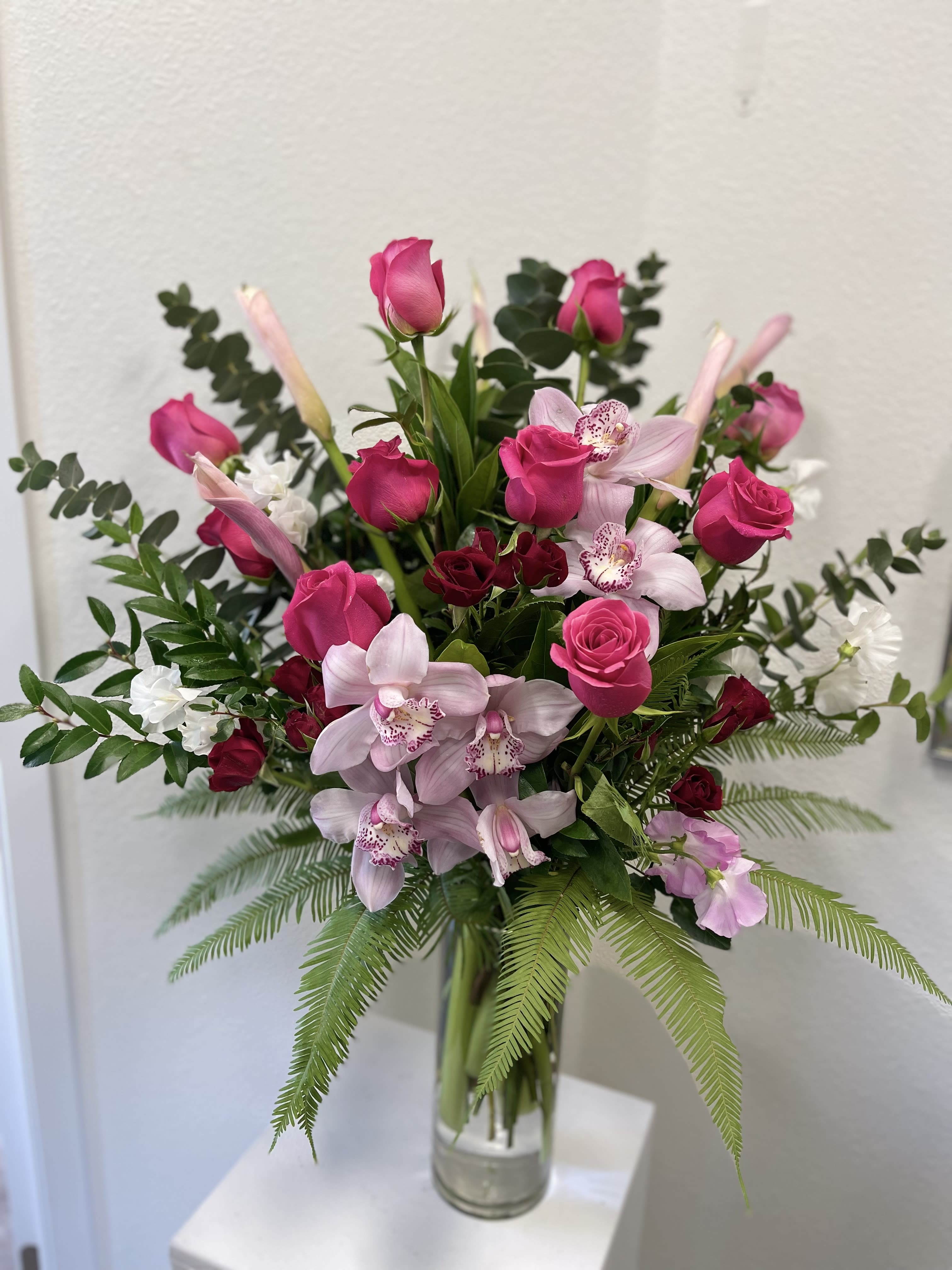 Pink roses and orchids arranged in a clear glass vase
