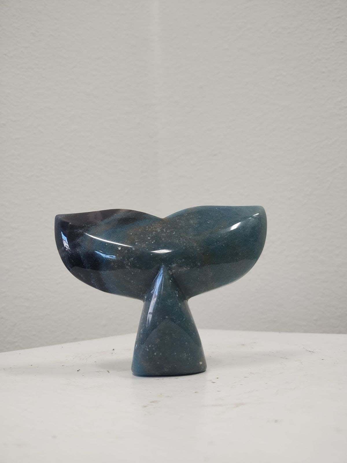 Dark blue whale tail sculpture on a white surface