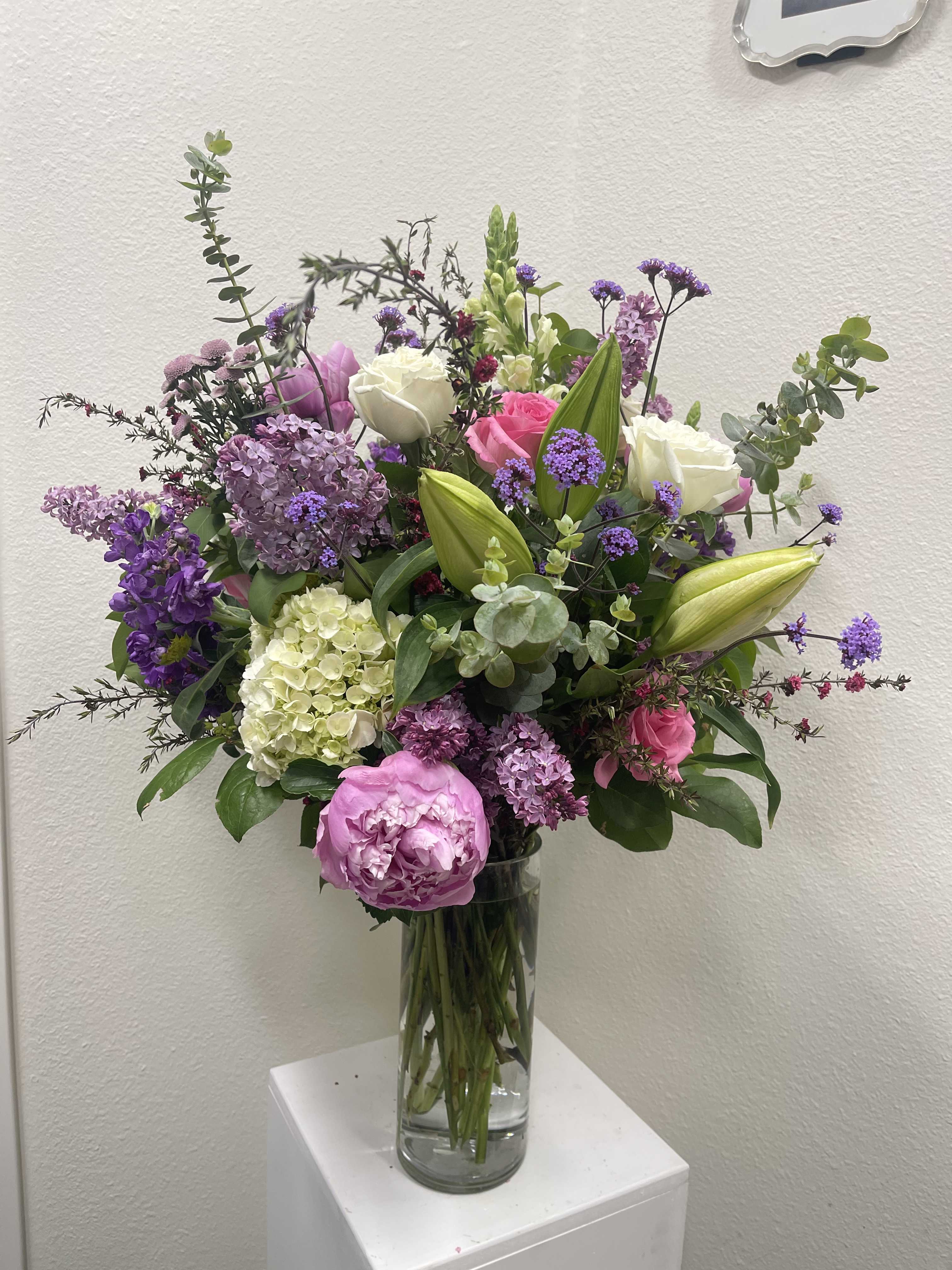 Mixed bouquet of pink, purple, and white flowers in a clear glass vase