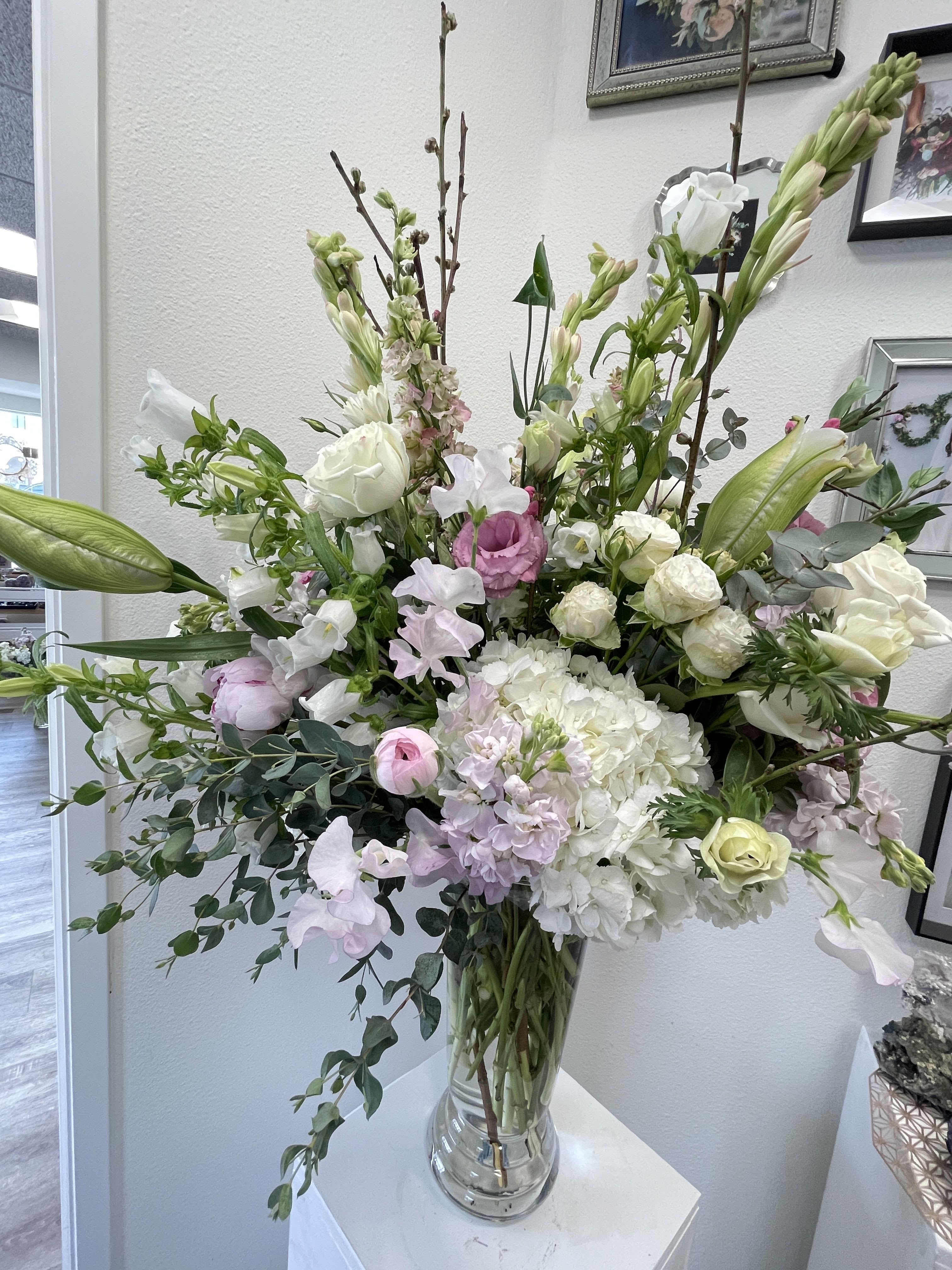 Tall bouquet of white and pale pink flowers in a clear glass vase