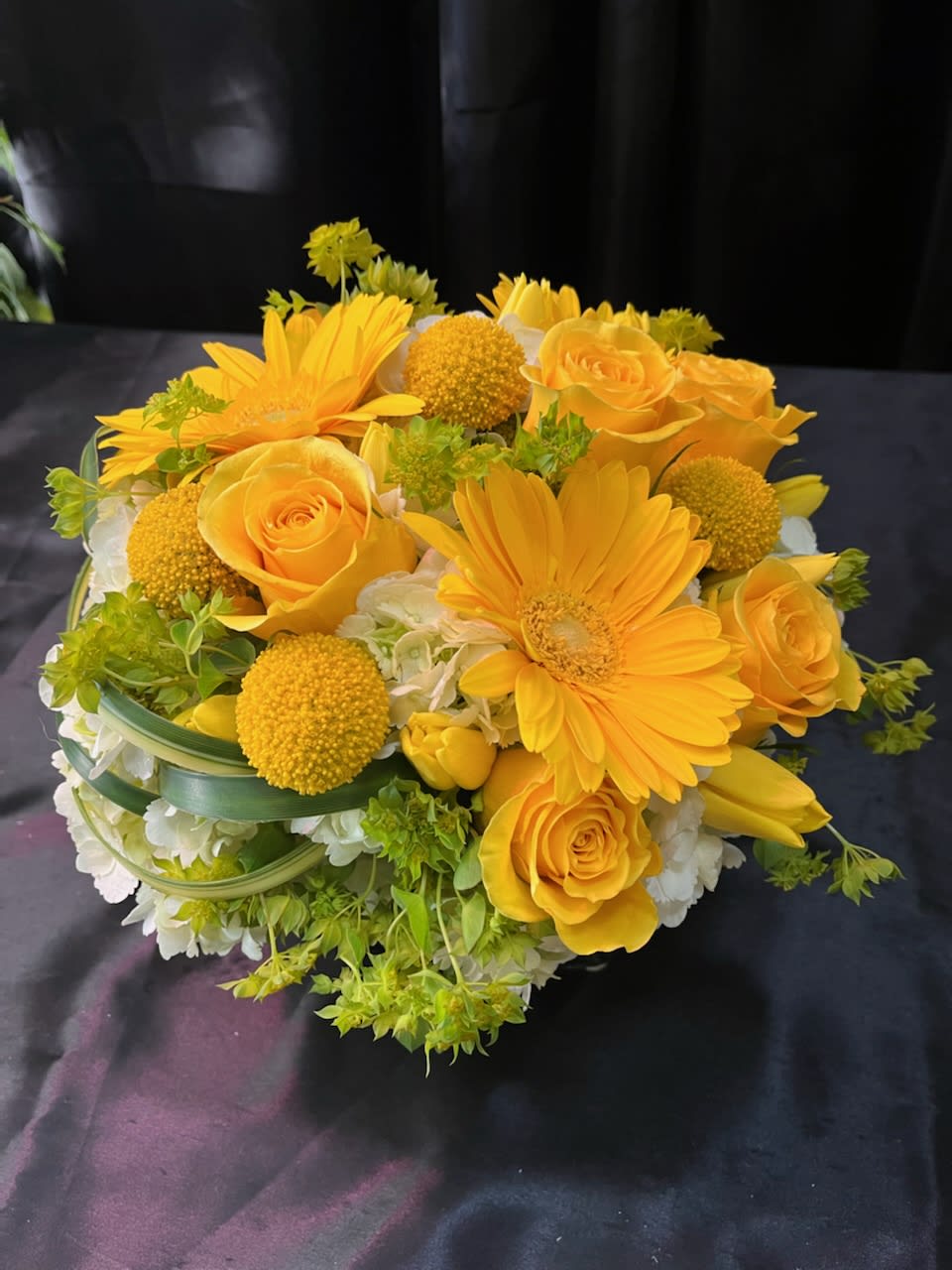 Yellow roses and gerbera daisies in a low bouquet with white flowers
