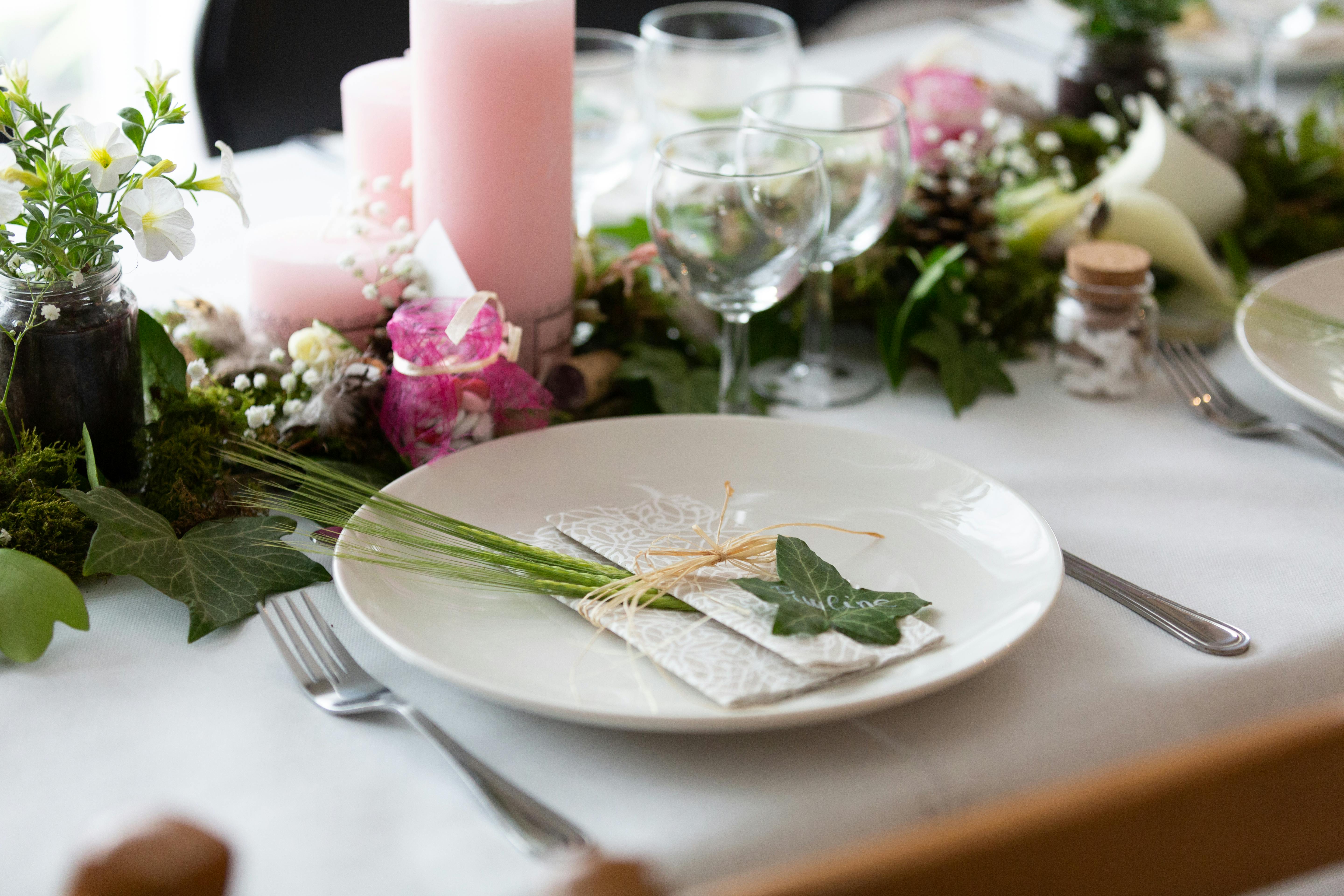 Floral table centerpiece with pink candles and white flowers on a set dining table