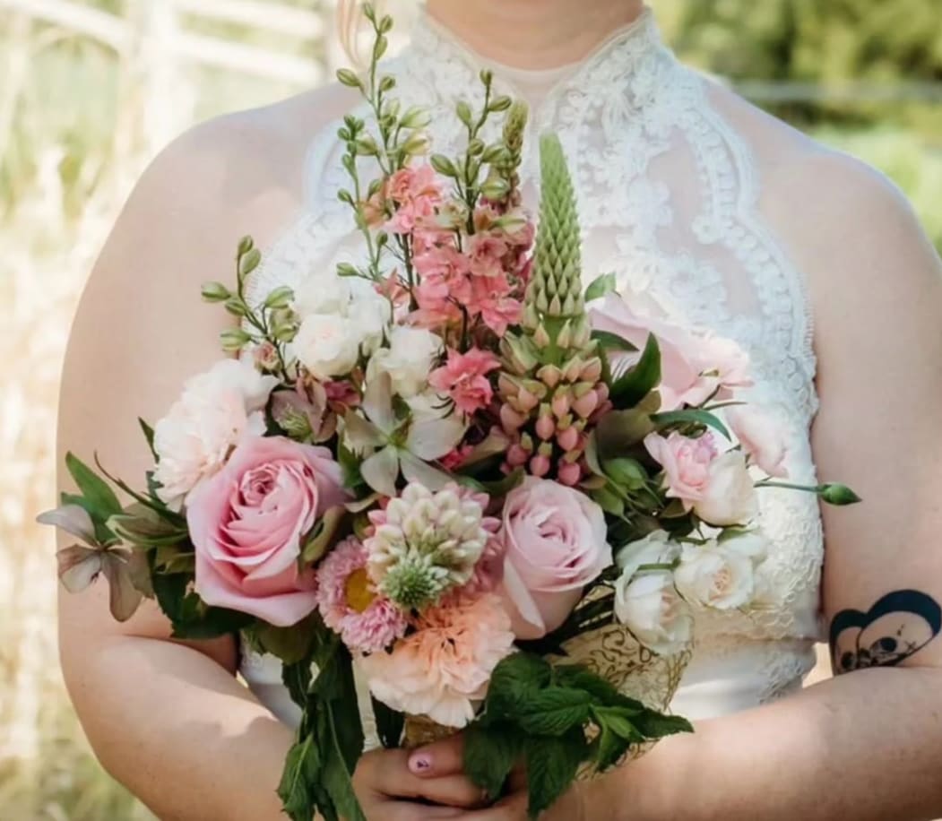 Bride holding a pink and white bouquet with roses and mixed blooms