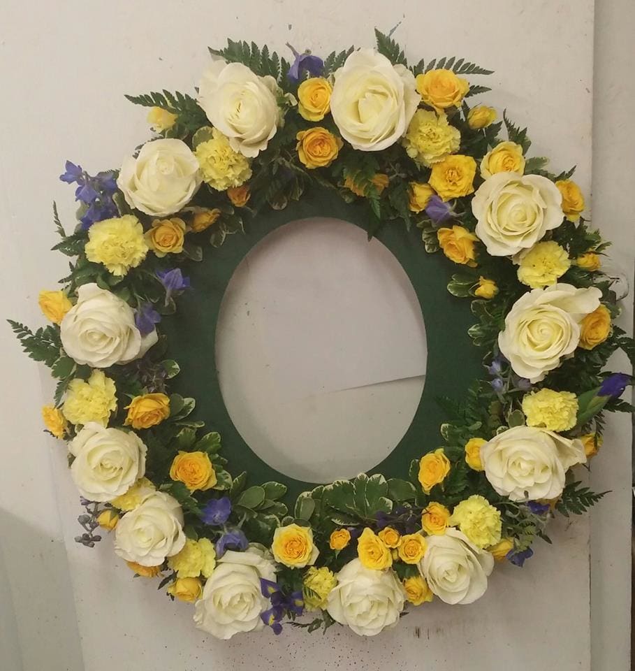 Circular floral wreath with white, yellow, and purple flowers