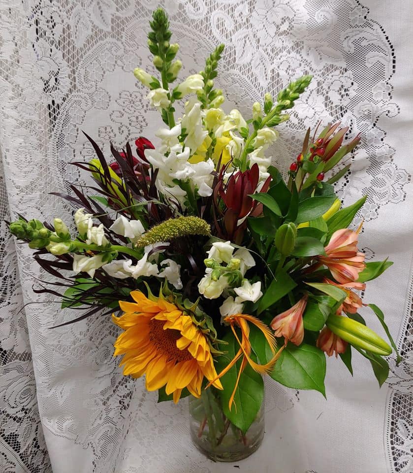 Mixed bouquet with sunflowers, white snapdragons, and lilies in a glass vase