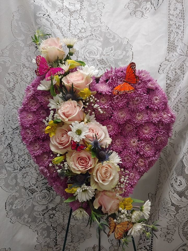 Heart-shaped floral arrangement with pink roses and purple blooms