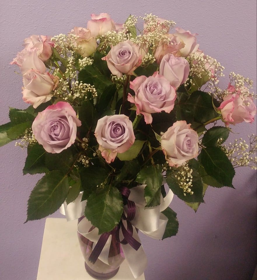 Bouquet of pale lavender roses in a glass vase with white ribbon