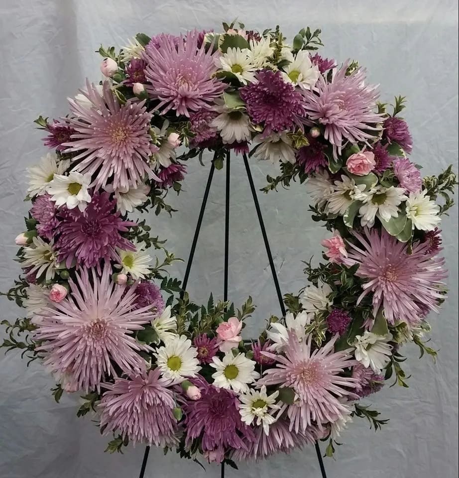 Lavender and white floral wreath on a black stand