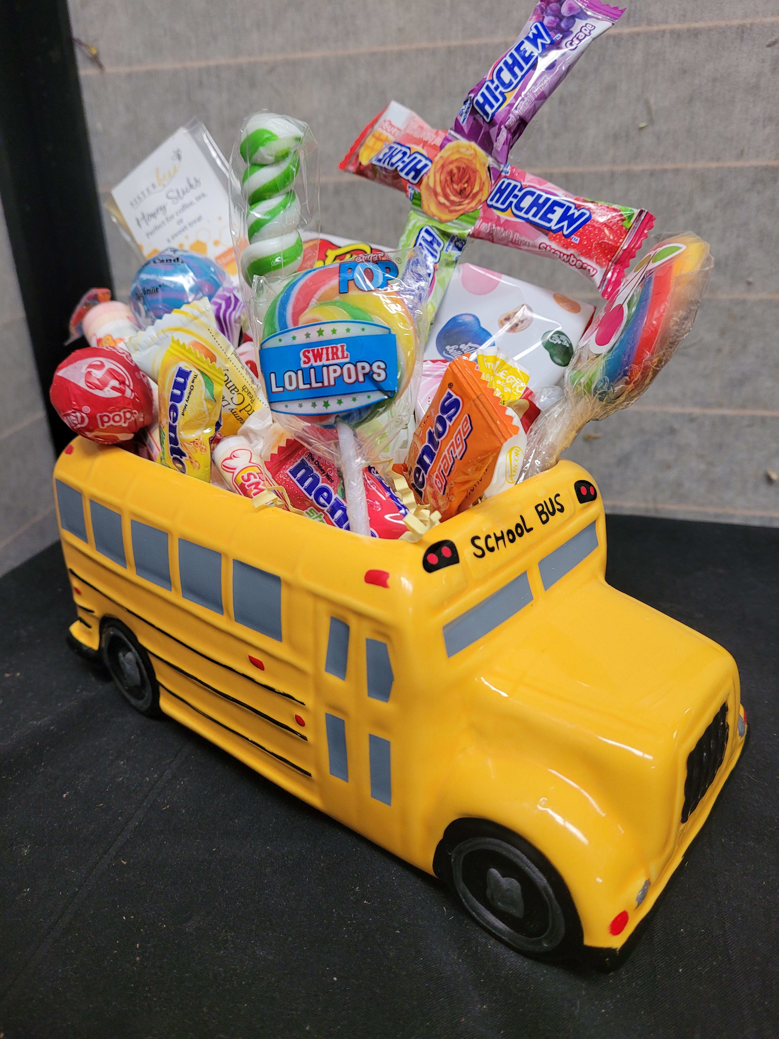 Yellow school bus-shaped candy container filled with assorted lollipops and sweets