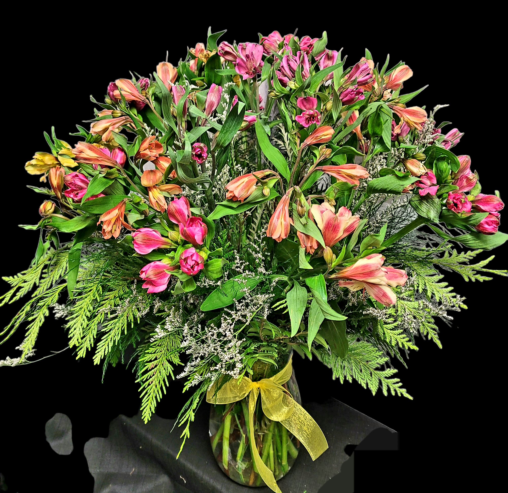 Pink and peach alstroemeria bouquet in a glass vase with a yellow ribbon