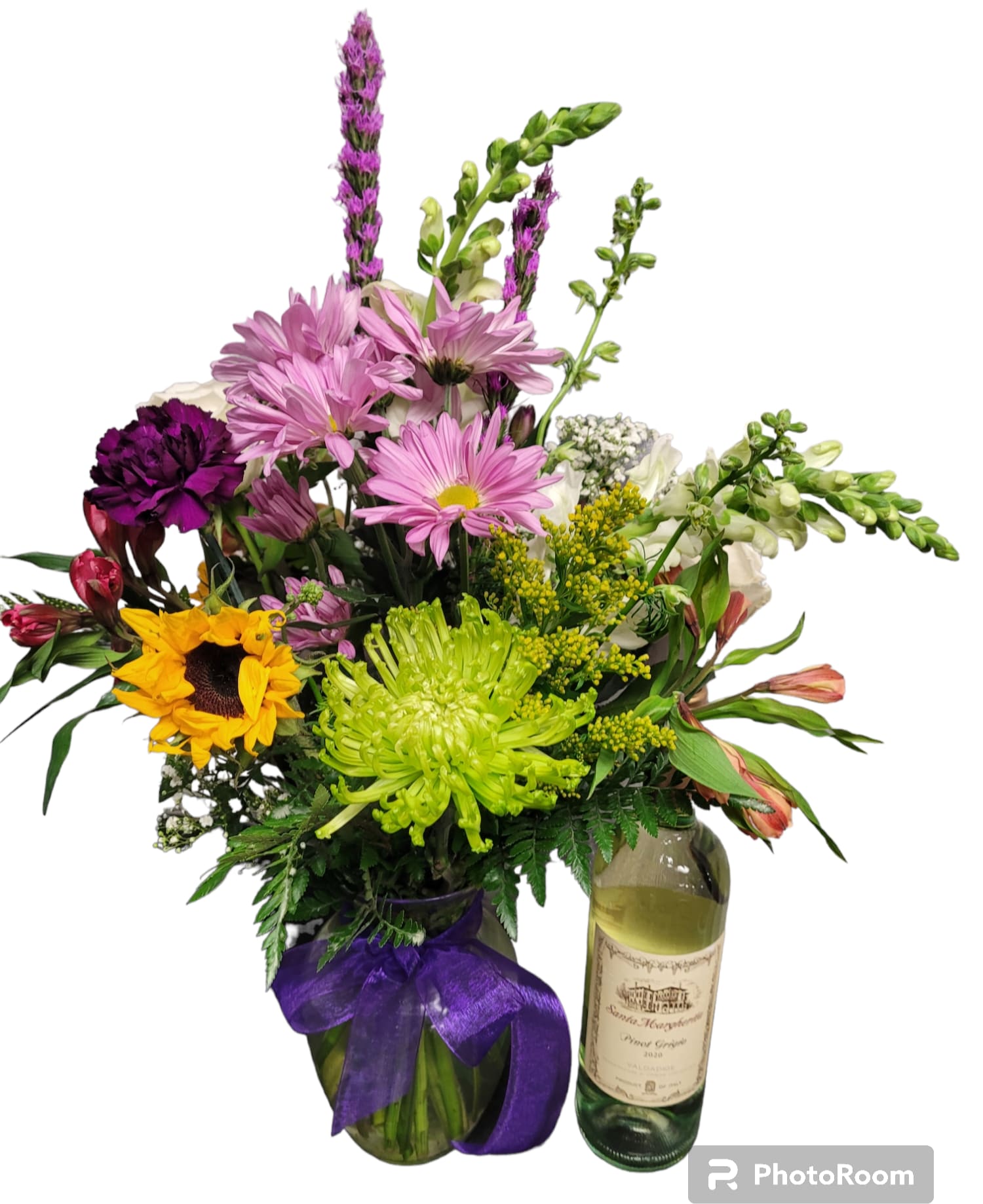 Mixed bouquet in a glass vase beside a wine bottle