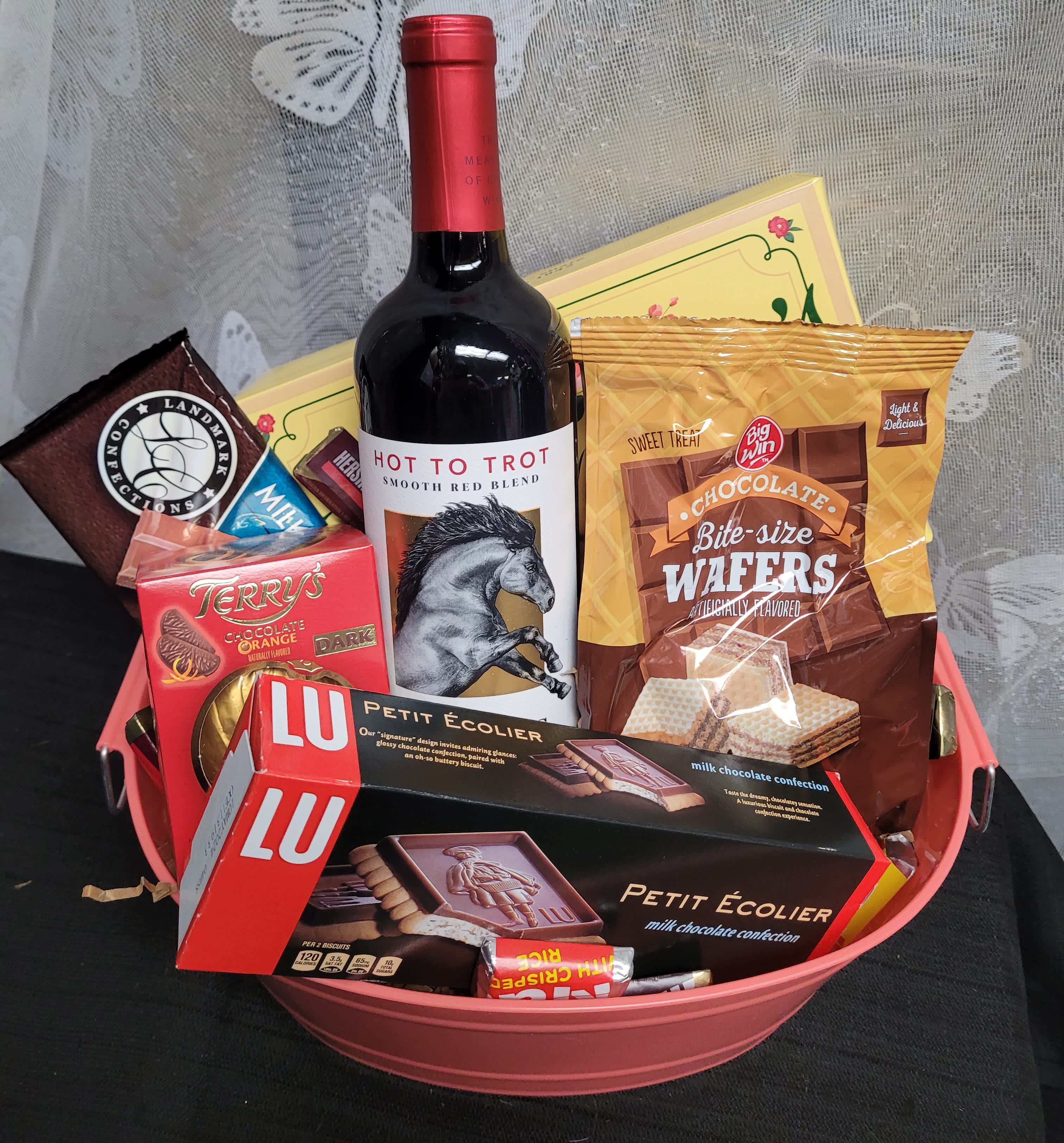 Gift basket with wine and assorted chocolates in a pink container
