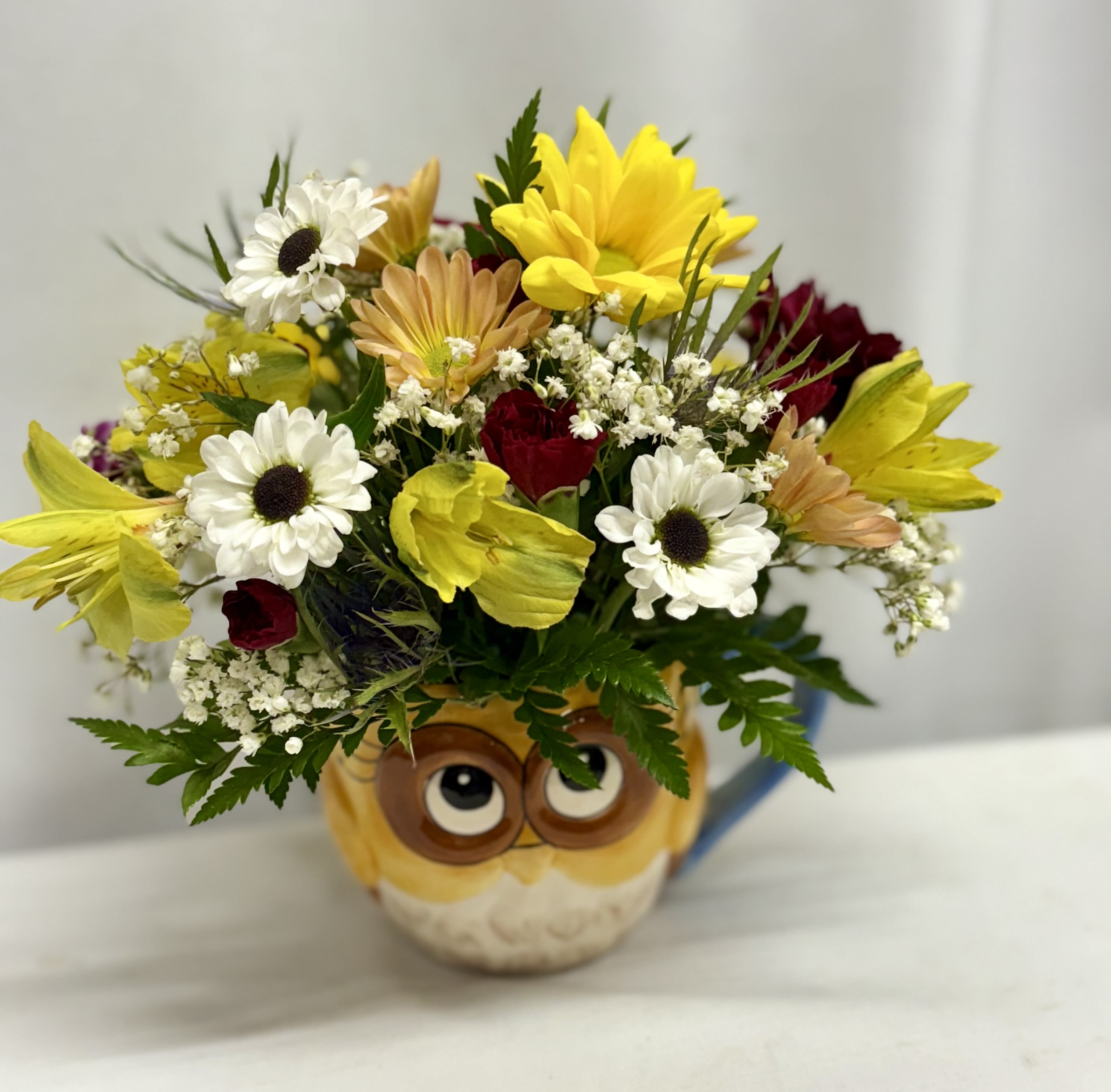 Bouquet of mixed flowers in an owl mug