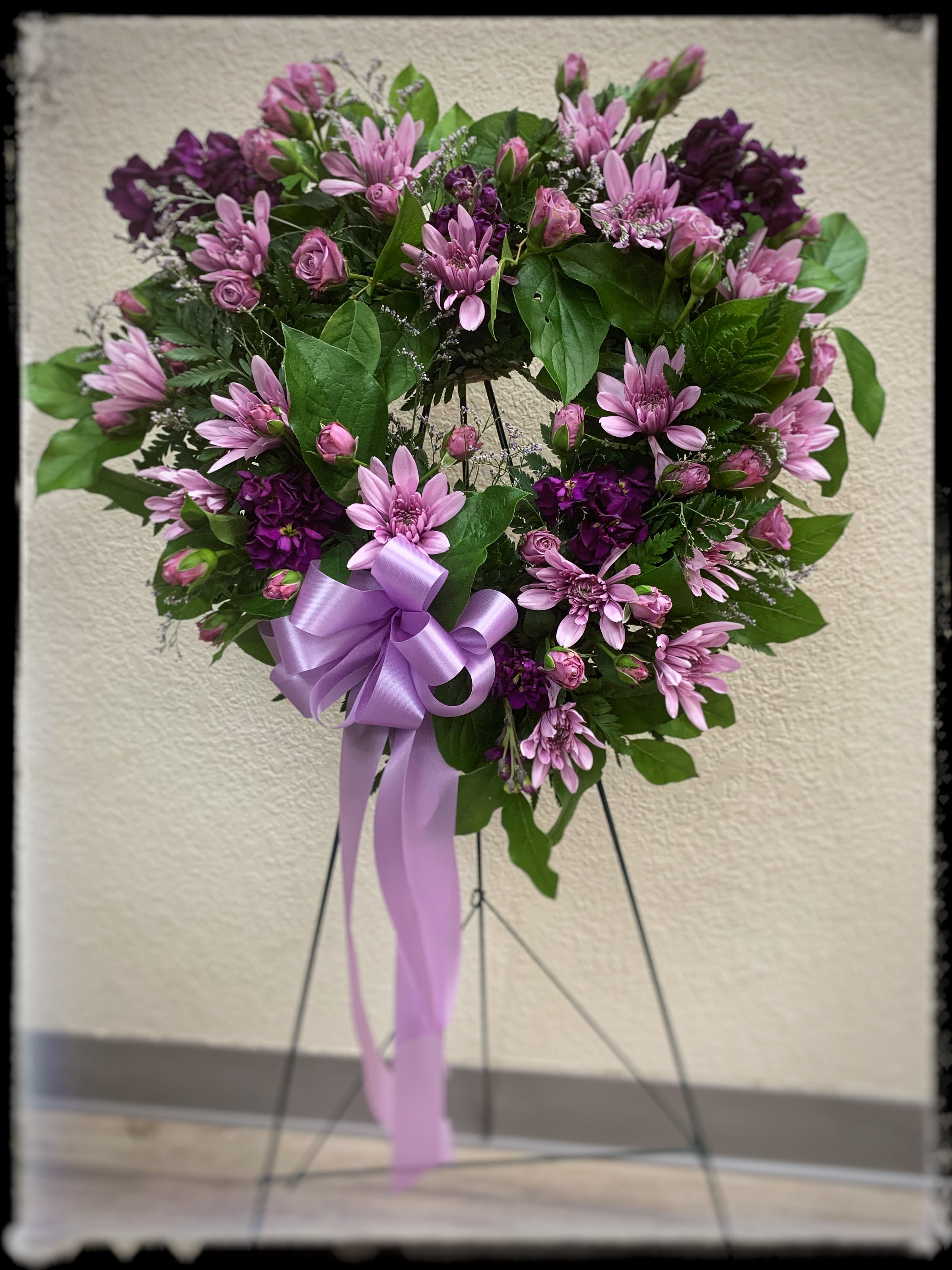 With All My Heart - Showing all your thoughts are with someone with this beautiful heart felt spray filled with lavender spray roses, purple stock, and purple cushion chrysanthemums.  Approximately 14". **When upgraded this arrangement includes more flowers, not a larger heart.** 