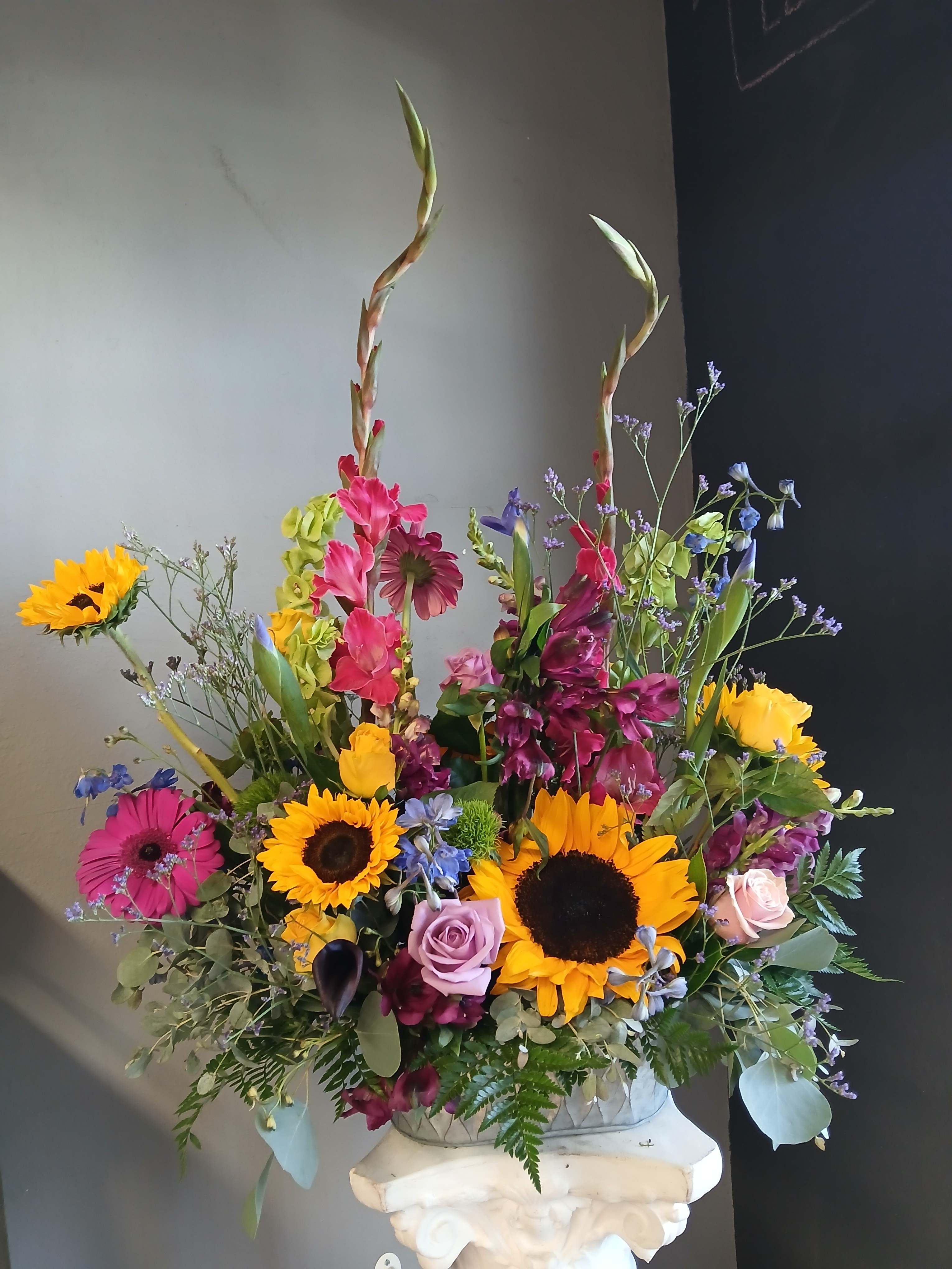 Colorful mixed flower arrangement with sunflowers, roses, and tall stems in a vase
