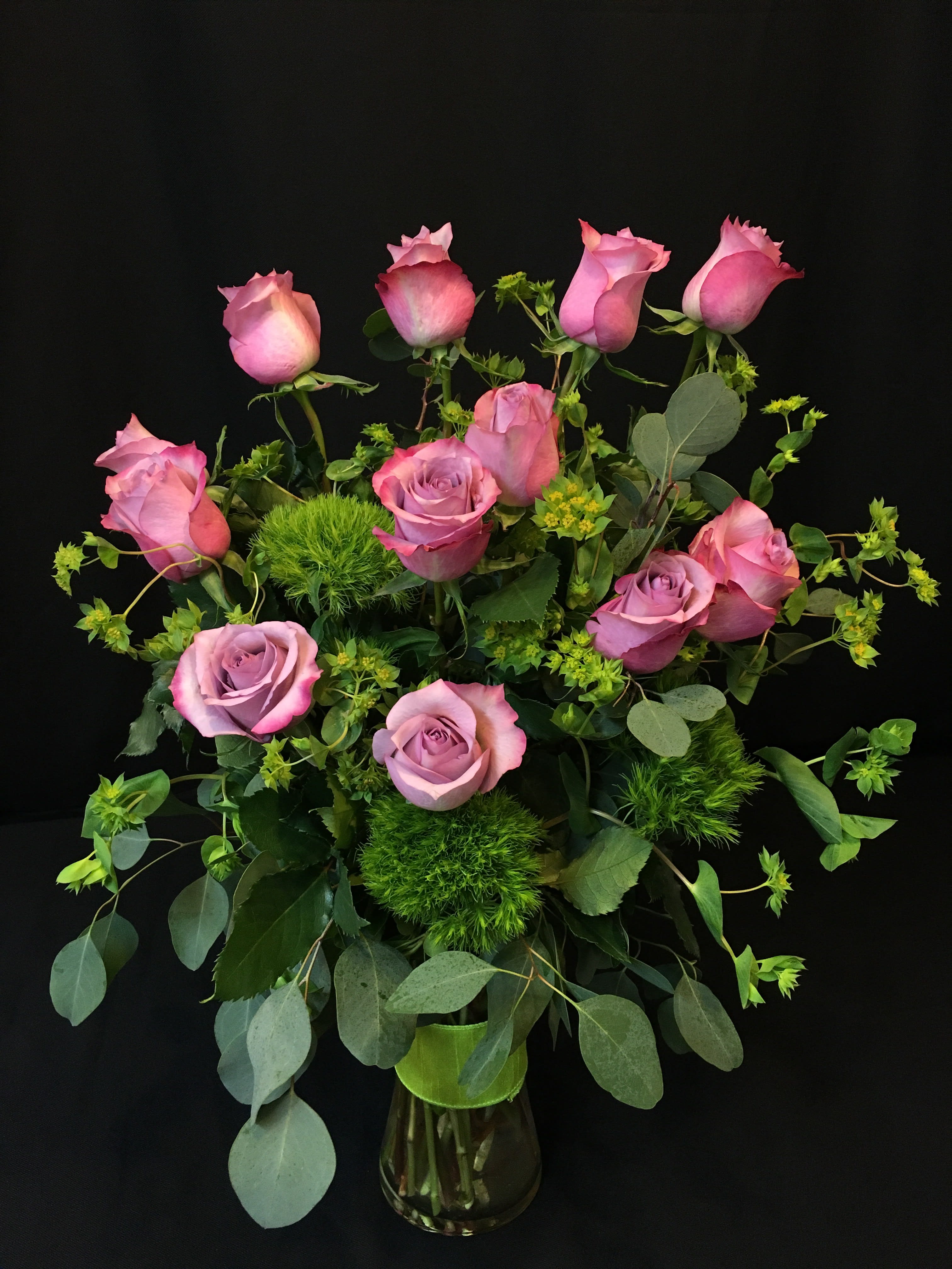 Pink roses arranged in a glass vase with greenery