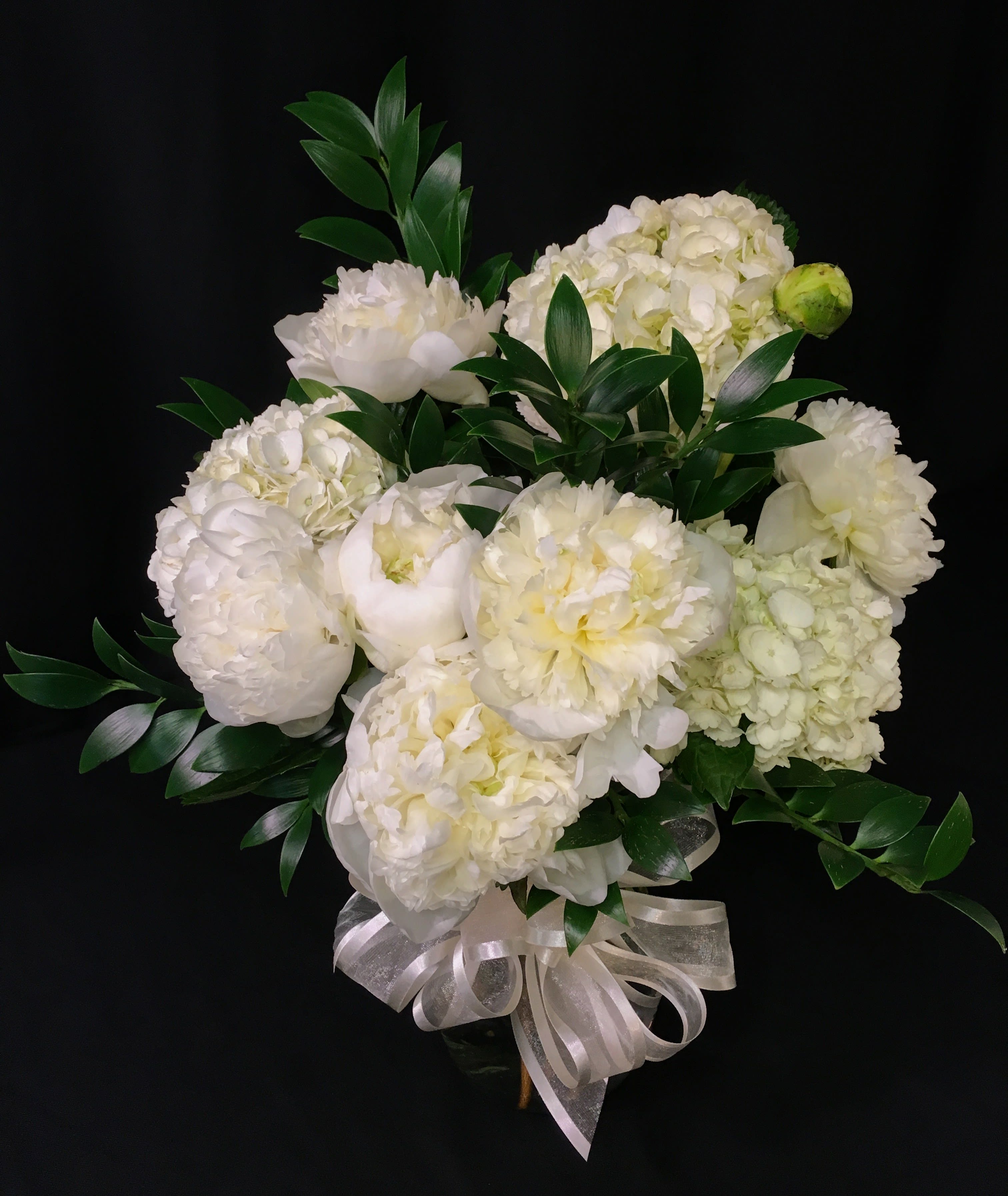 White floral bouquet with green foliage and a ribbon bow