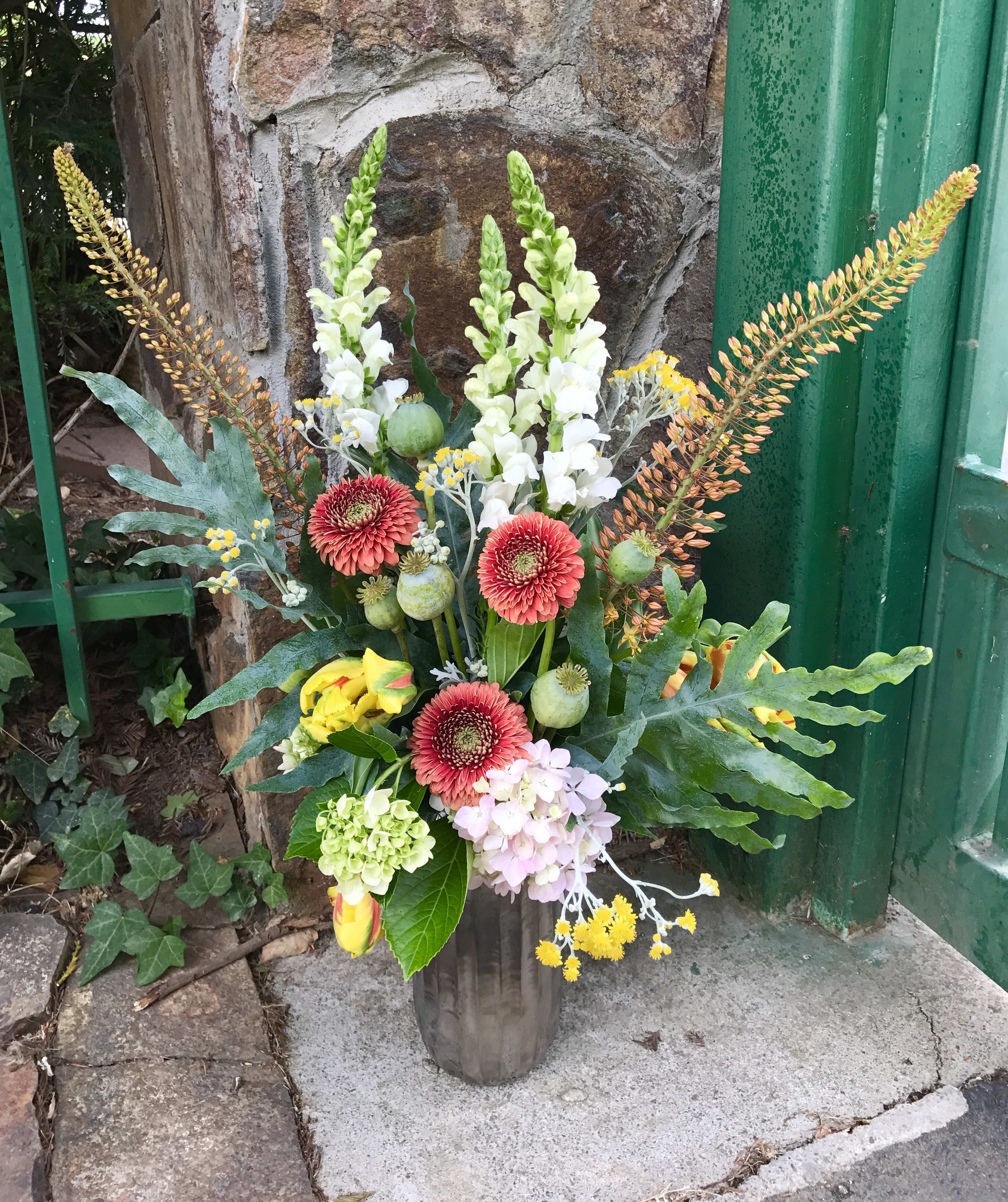 Tall Poppy pod mix in Treasured vase - Eremeris, poppy pods and snapdragon make a lovely and elegant tall creation.  Flowers will vary with the seasons.  Container choice will vary and will be a premium upgraded vase. Mixed bouquet of exquisite premium flowers.