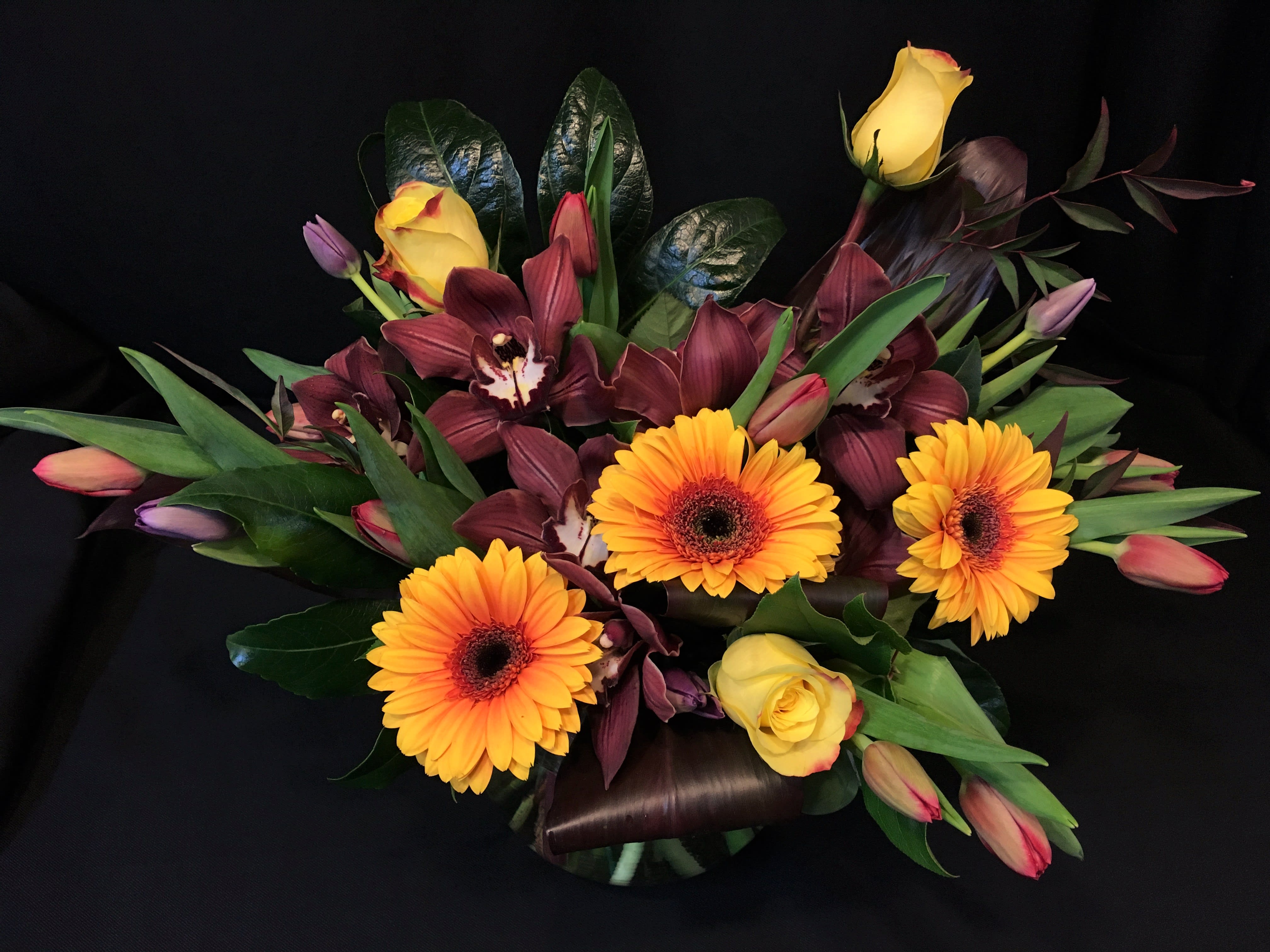 Bouquet of yellow roses, orange gerbera daisies, and burgundy orchids