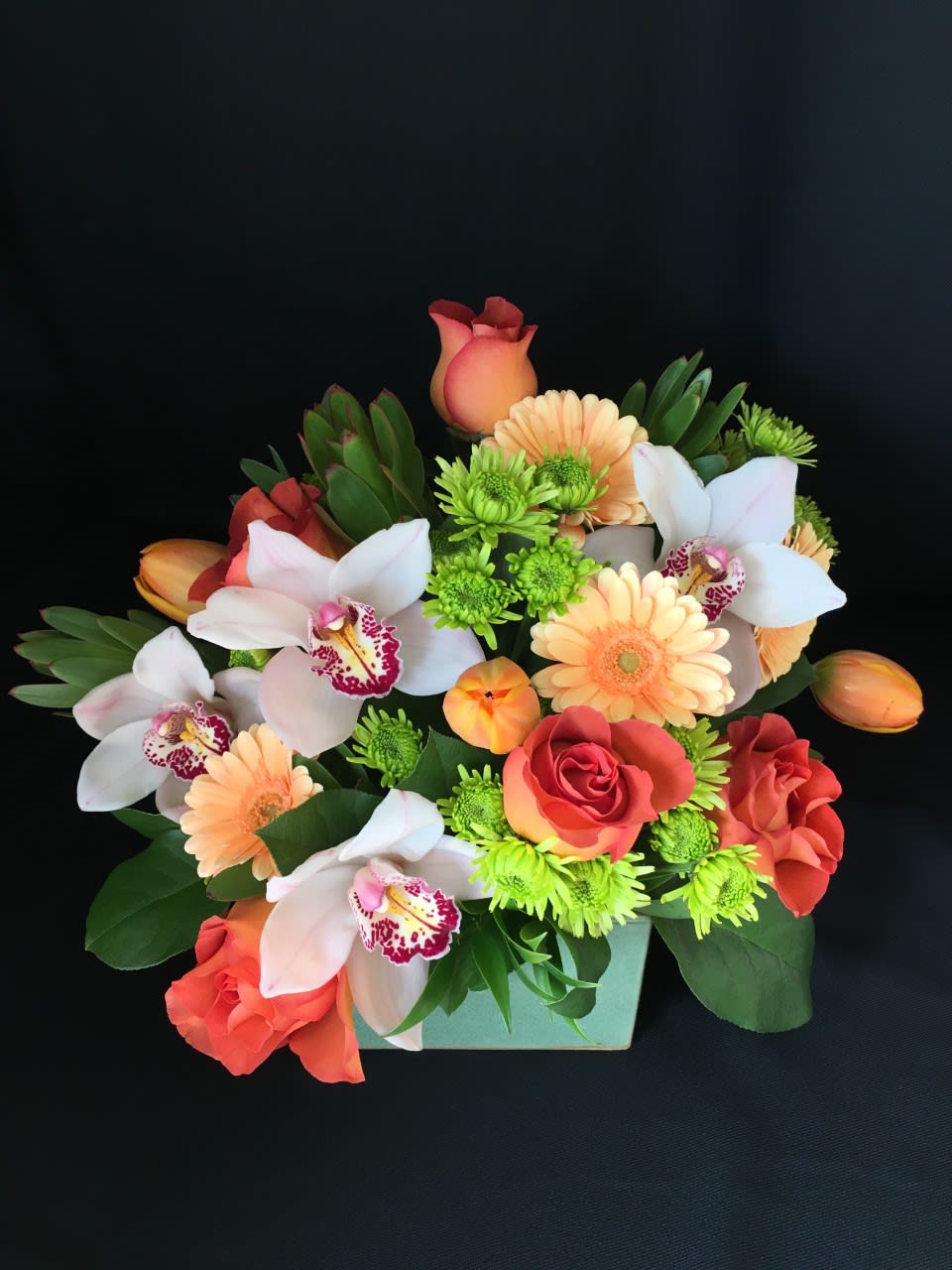 Rose cymbidium cube with orchids - This pretty cube includes roses and Cymbidium orchids along with beautiful seasonal accent flowers. Sweet gift of love without being overwhelming in size. Container and color may vary.  