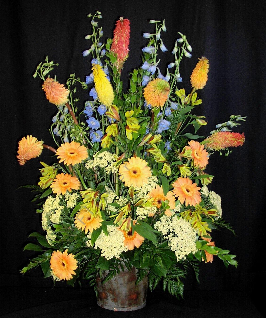 Spring Basket Spray for Funerals and Memorials - Large arrangement for a big space such as a large church or synagogue.  Full and tall with lots of pretty flowers that can be adjusted for any time of year.  Spring flowers are shown. Assortment will vary.  Provide color requests at least a few days prior and/or we will do our best to provide them.  Flowers will be in a basket (style may vary) of floral foam for stability.