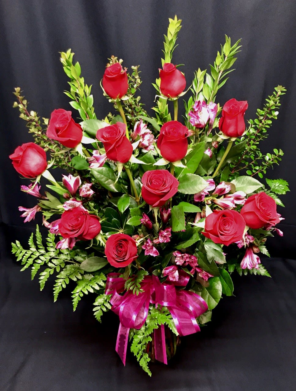 Red roses and pink alstroemeria in a tall bouquet with a magenta ribbon