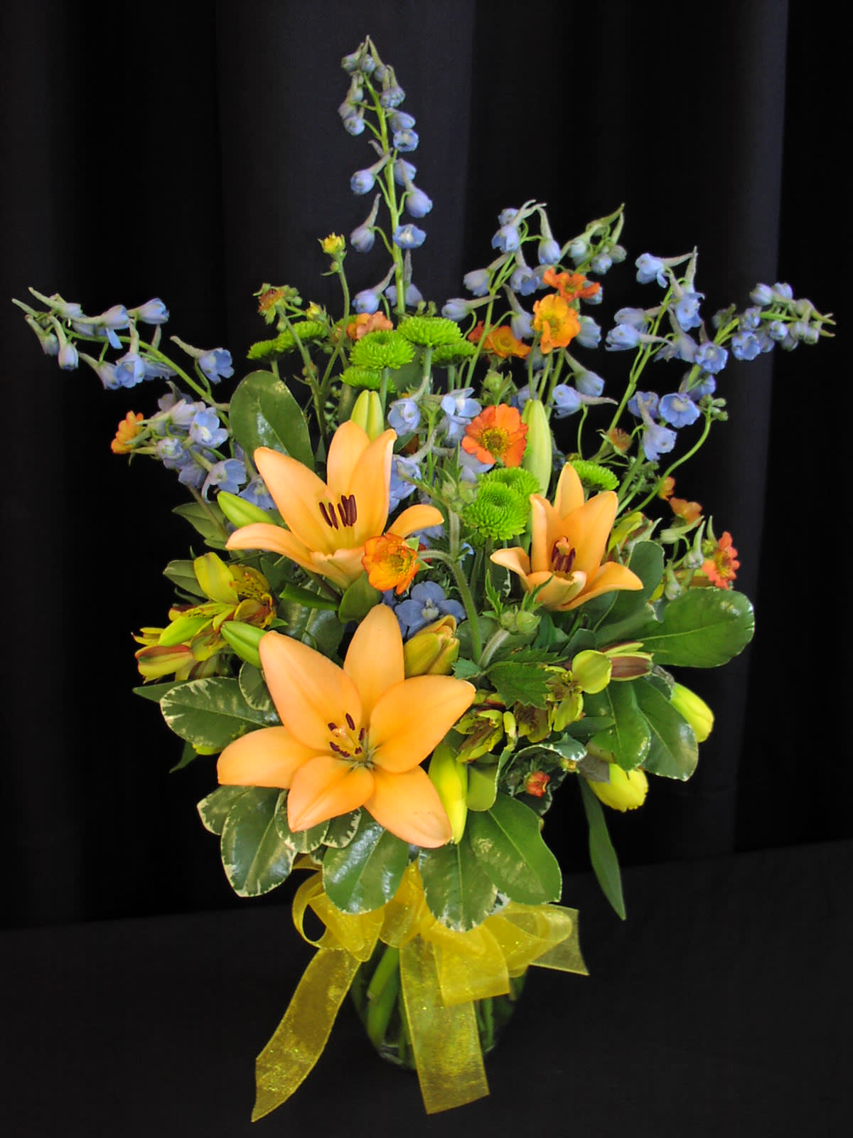 Small spring mix with Daffodil - Our small vased arrangement with the best of spring's bounty.* Selection and colors will vary. Shown here are sky blue bella donna, alstromaria, peach lilies, green button mums, geum and the lovely little sign of spring itself, THE DAFFODIL!  YES! This comes in Valentine colors! May cost $5 more during Valentine's and Mother's day holidays.