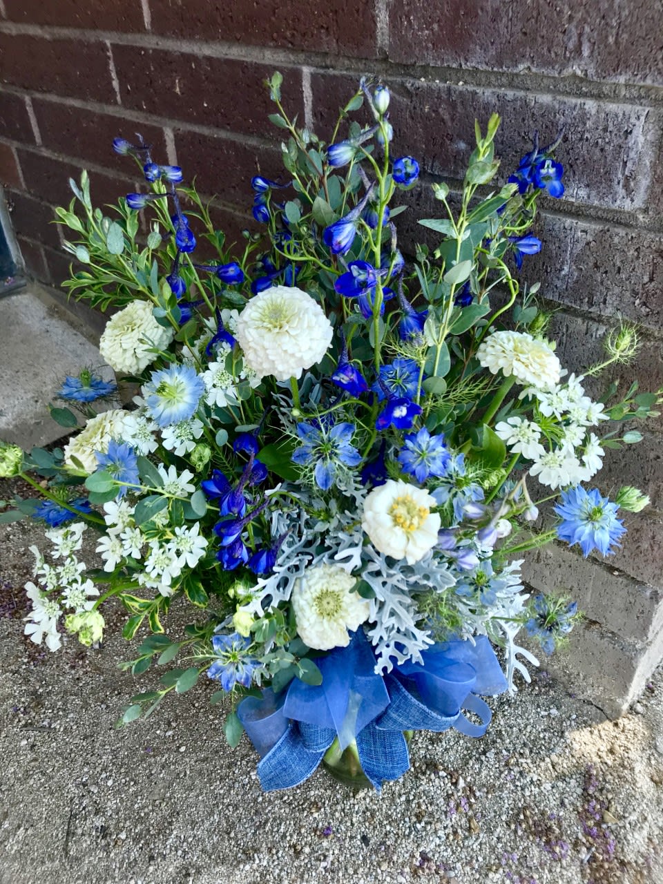 Blue and white mixed flower arrangement with ribbon at the base