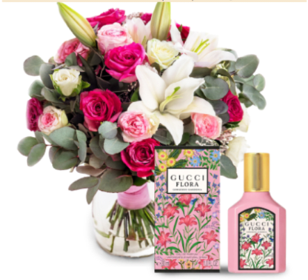 BLOSSOM BLISS HEART - A lush cluster of pink and white roses with creamy white lilies forms the heart of this romantic flower arrangement - perfect as a birthday bouquet, anniversary gift, or Mother's Day surprise. Rounded eucalyptus adds soft green texture and a subtle, fresh scent so the person you're celebrating will feel both seen and pampered the moment the vase is set down.  The flowers arrive gathered in a clear glass vase tied with a soft pink ribbon for a polished, gift-ready presentation. Alongside the arrangement is a matching pink perfume bottle and a decorated perfume box, creating a coordinated gift set that pairs blooms and fragrance for an extra-special reveal. The palette of pink, white, and green reads feminine and celebratory, ideal for someone you want to make feel cherished.