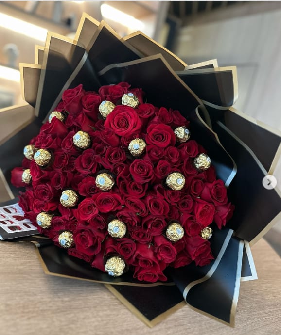 Bouquet of red roses with gold-wrapped chocolates in black paper