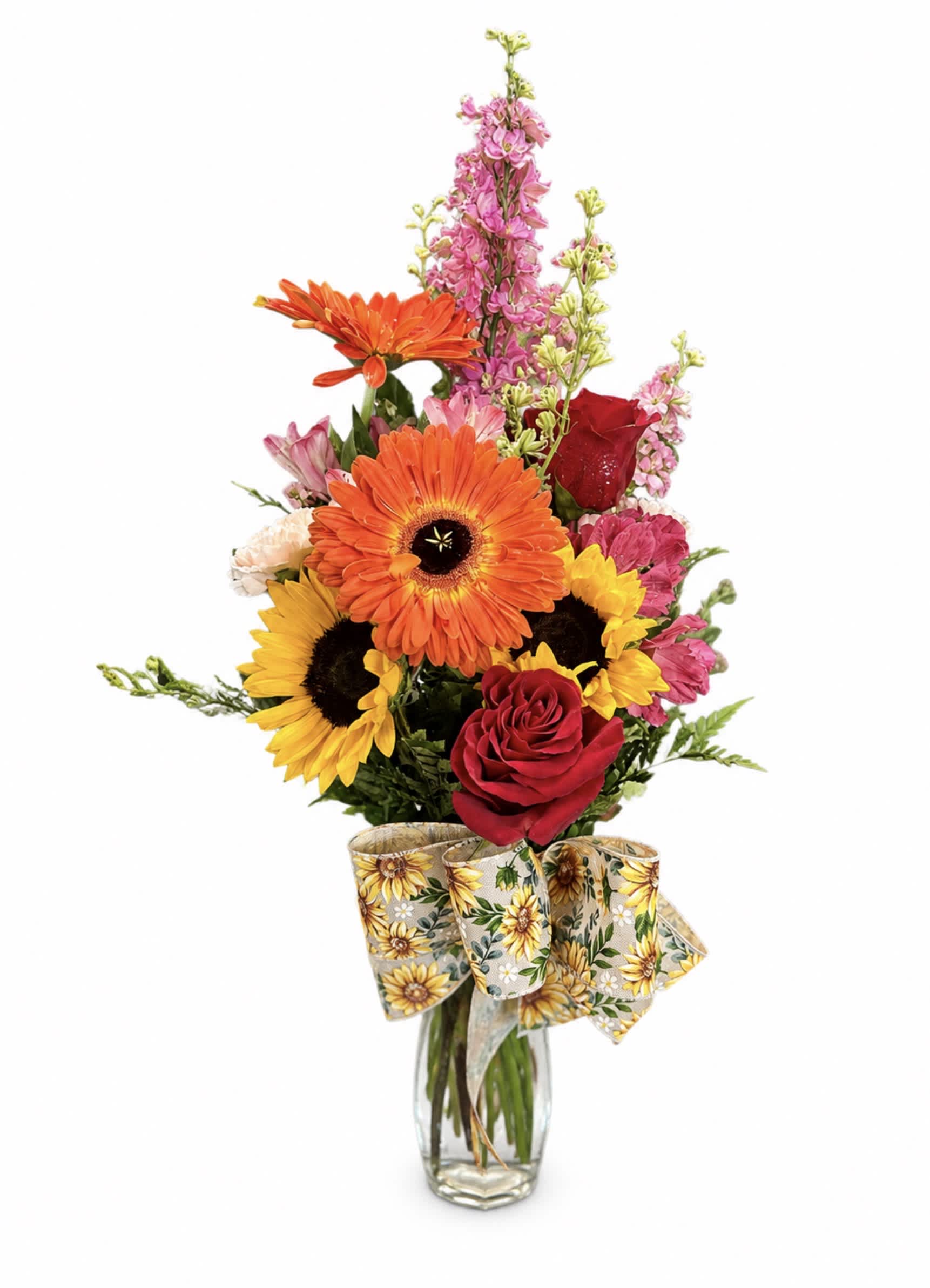Mixed bouquet with sunflowers, gerbera daisies, roses, and pink blooms in a glass vase