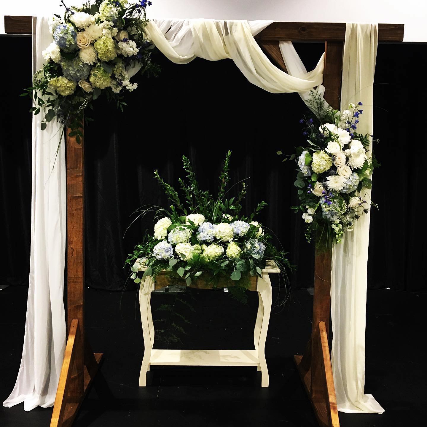 Wedding Arch  - LOCAL RENTAL  of our beautiful handmade wooden wedding arch draped with white and ivory fabric. Includes 2 floral pieces in your color palate , set up and retrieval before and after the ceremony. Back table floral arrangement is not included but can be added as an upgrade  ( table not included) 