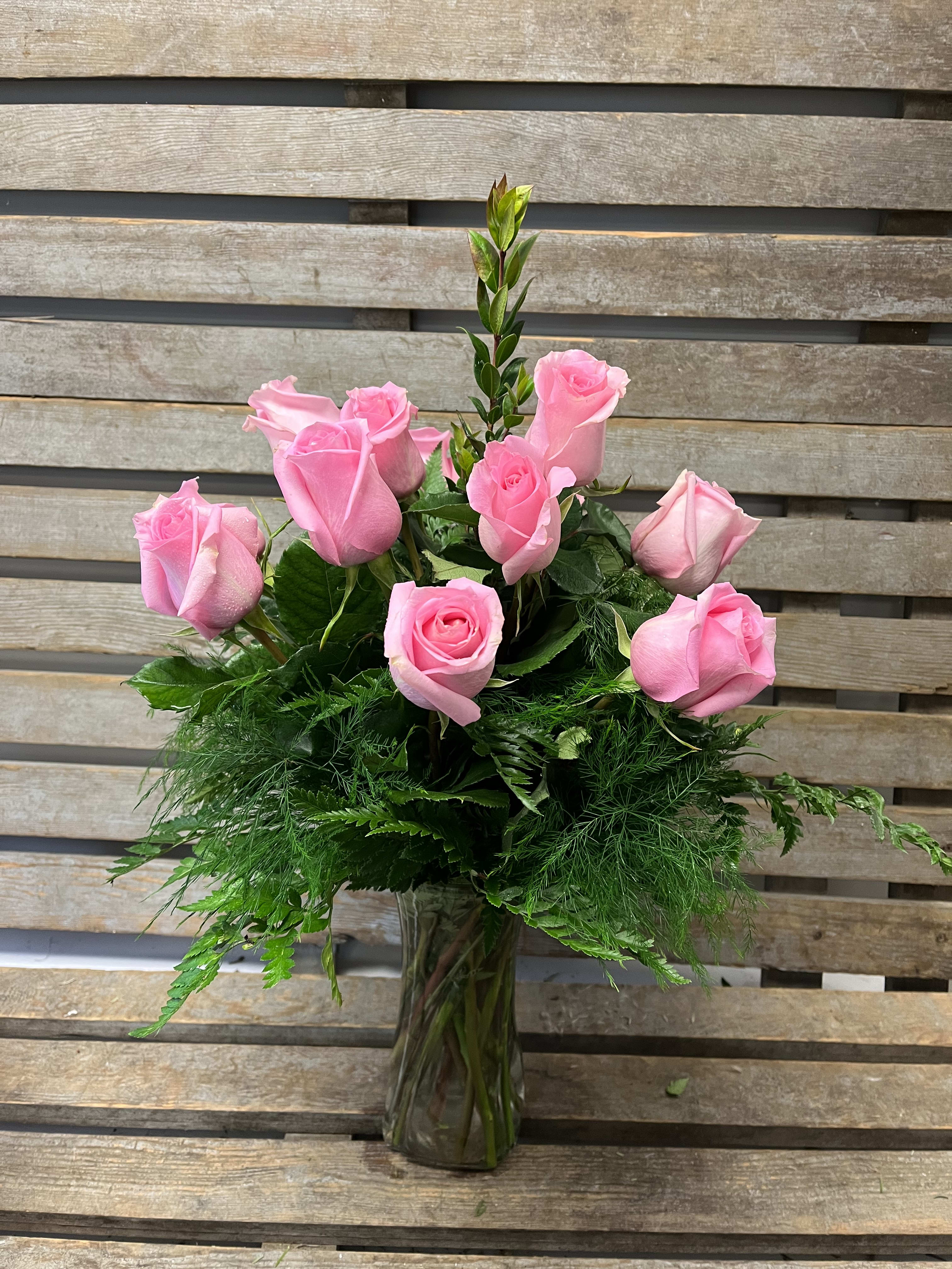 Pink roses arranged in a clear glass vase with lush greenery
