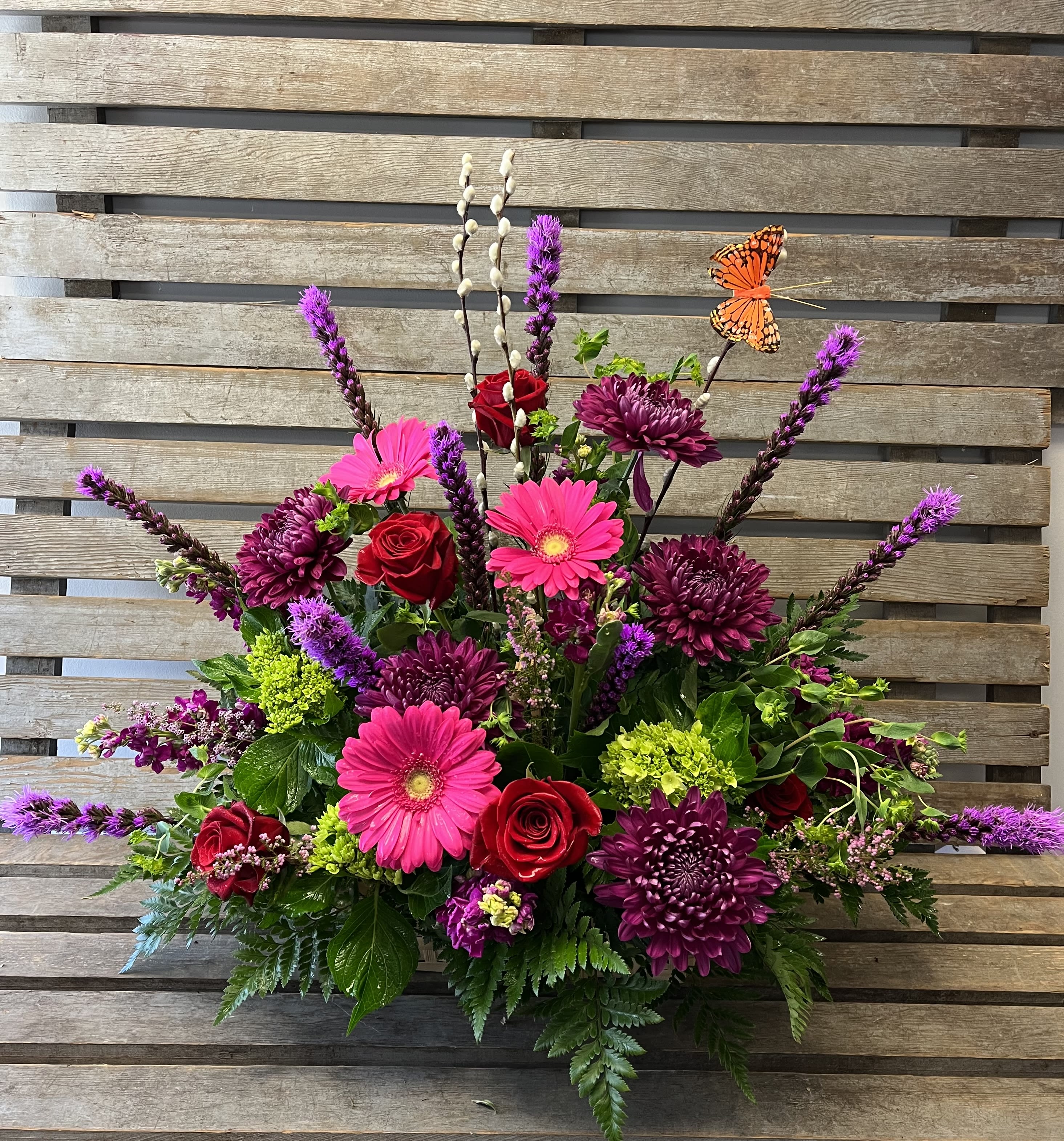 Bright mixed flower arrangement with roses, gerbera daisies, and purple blooms