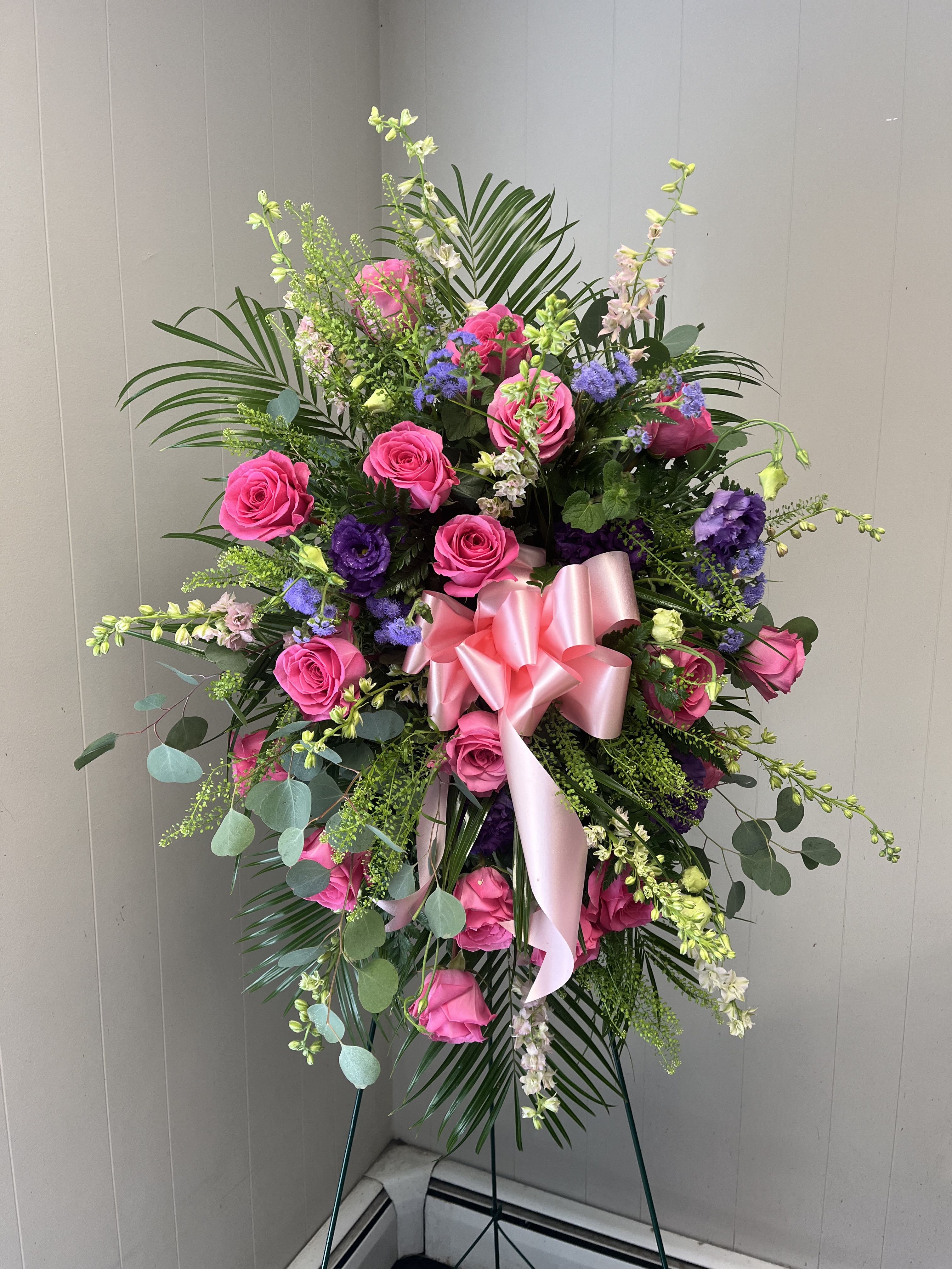 Standing floral spray with pink roses and purple blooms on an easel