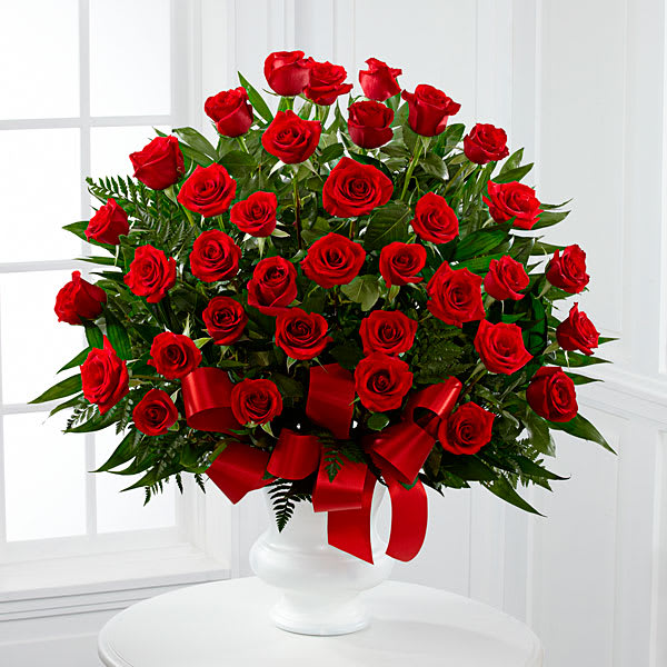 The FTD Soul's Splendor Arrangement - The FTD® Soul's Splendor™ Arrangement is a rich display of the love shared throughout the life of the deceased. Brilliant red roses are elegantly displayed in a white designer plastic urn and accented with lush greens and red satin ribbon to create a beautiful tribute to honor your special relationship.