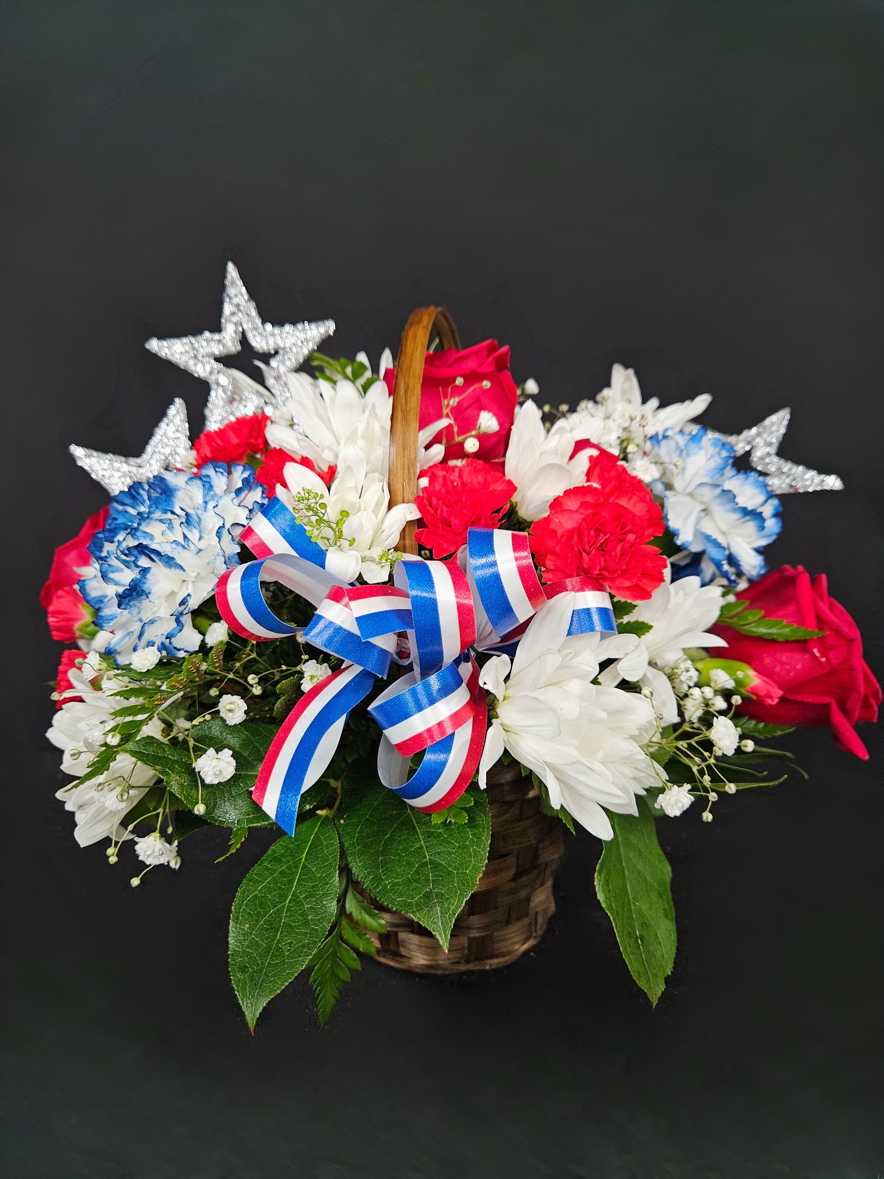 Basket of red, white, and blue flowers with star decorations and ribbon