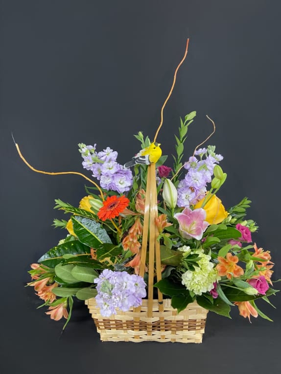 Mixed flower basket with a bird decoration and tall curly branches