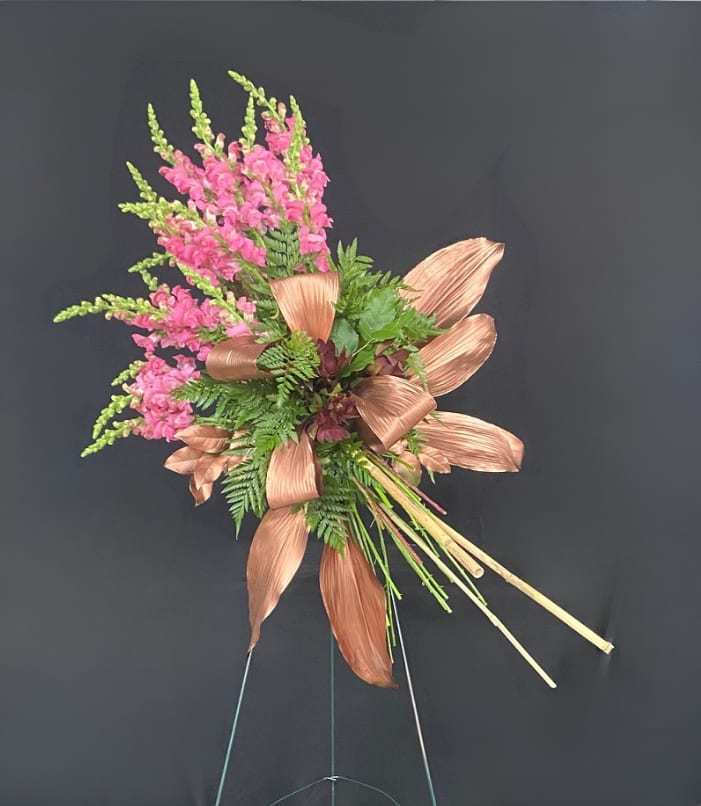 Pink floral spray with copper-toned leaves on a stand