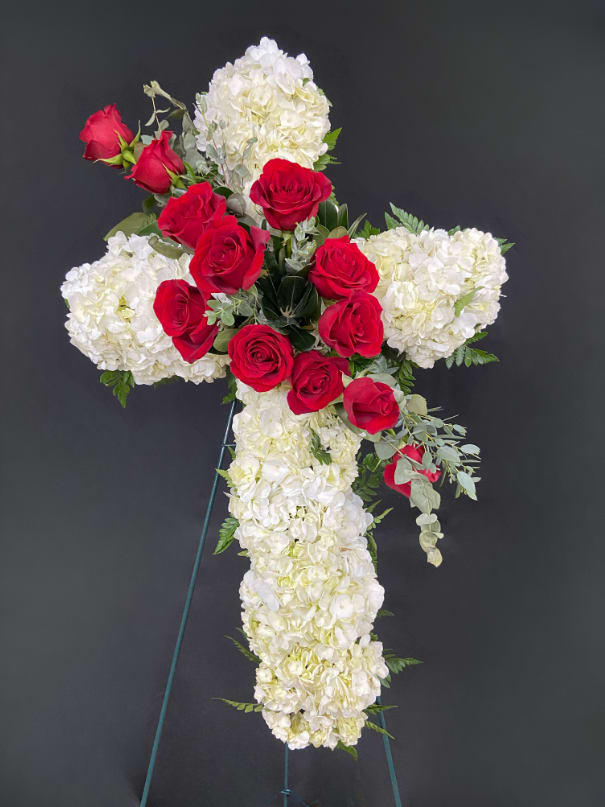 Heavenly Cross Standing Spray - A cross form covered in white hydrangeas or carnations with a rose sash cutting across the design (your choice of colors). Displayed on a 54" standing easel. Available in 24" (standard) and 30" (deluxe) sizes.