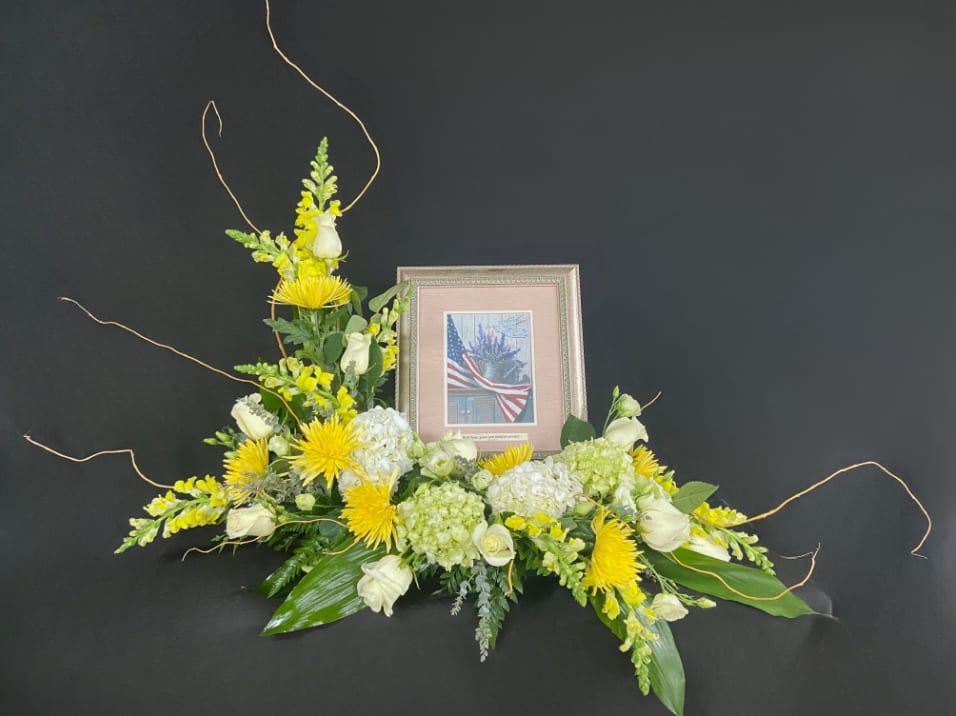 Yellow and white floral tribute with a framed photo centerpiece