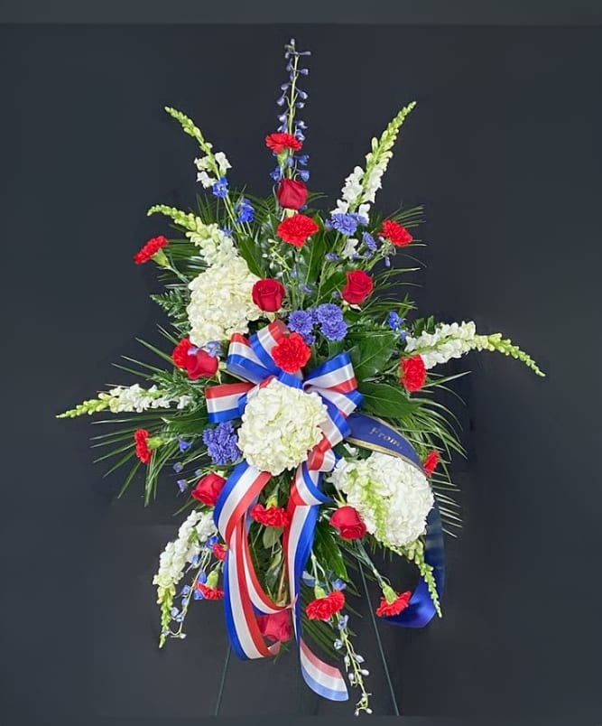 Standing floral spray with red roses, white hydrangeas, and blue accents