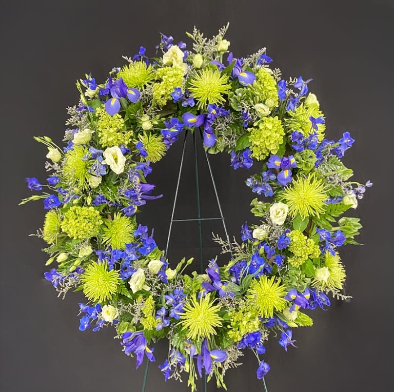 Circular floral wreath with blue and lime-green flowers on a stand