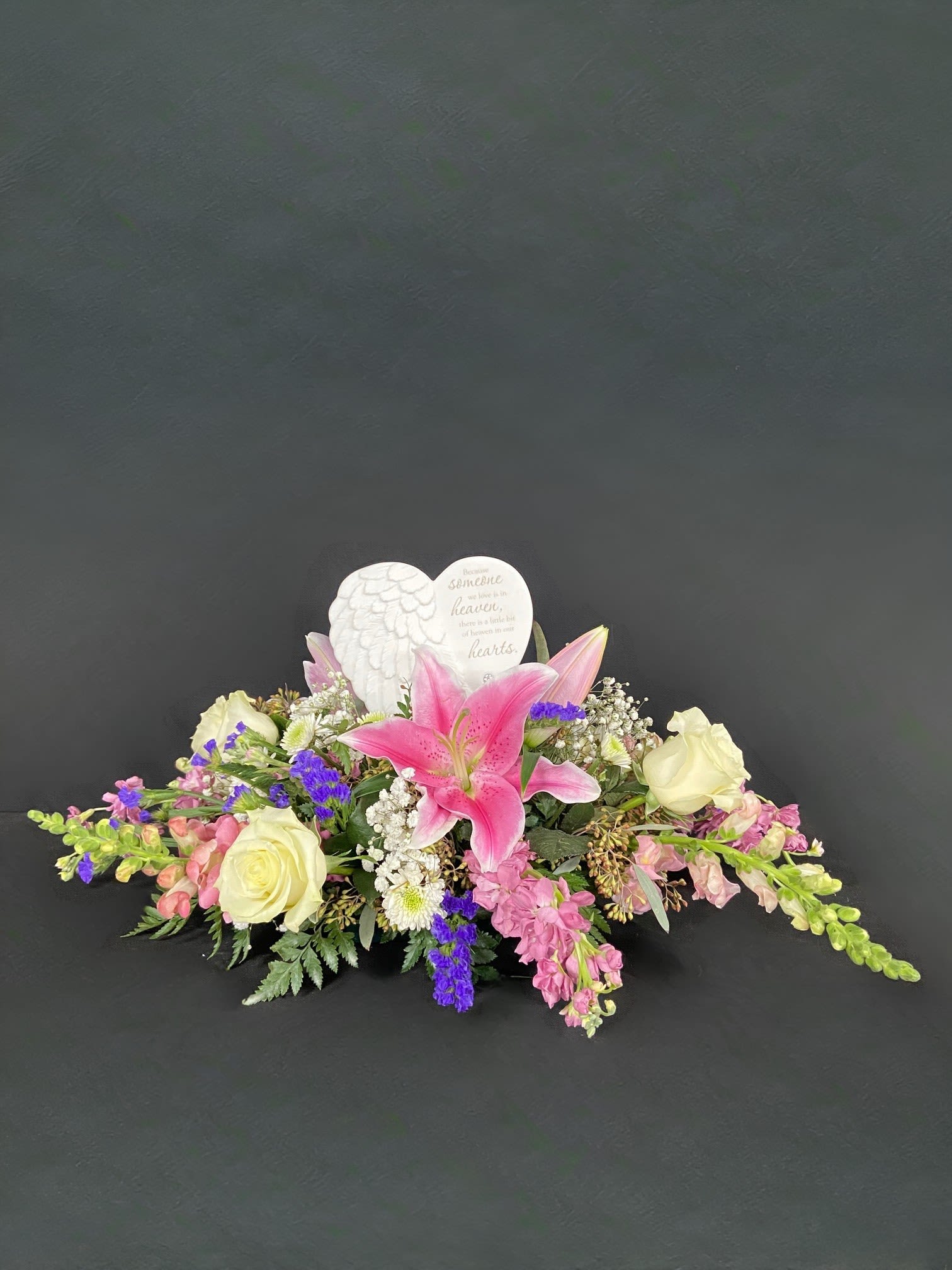 Sympathy floral arrangement with pink lilies and cream roses around a heart memorial plaque